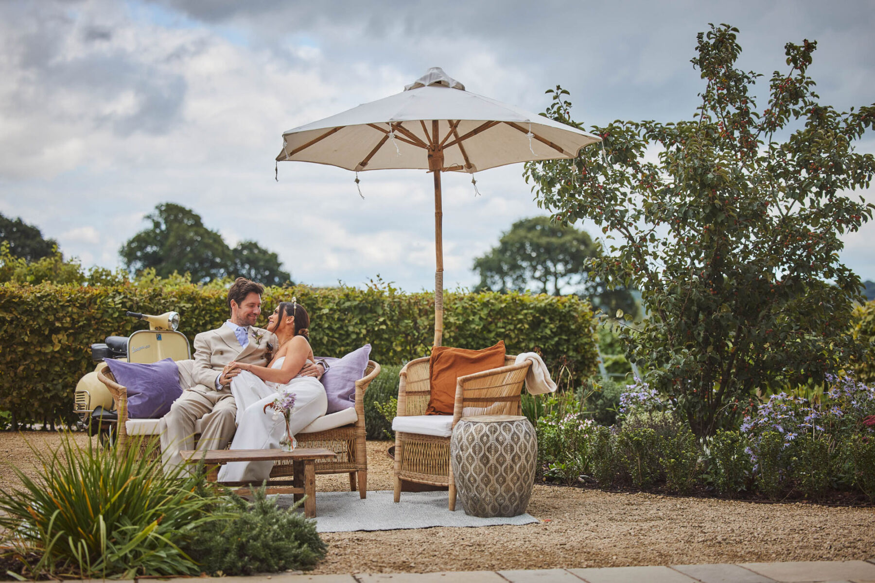 Couple relaxing under parasol in the gardens at Brickhouse Vineyard - Devon wedding venue.