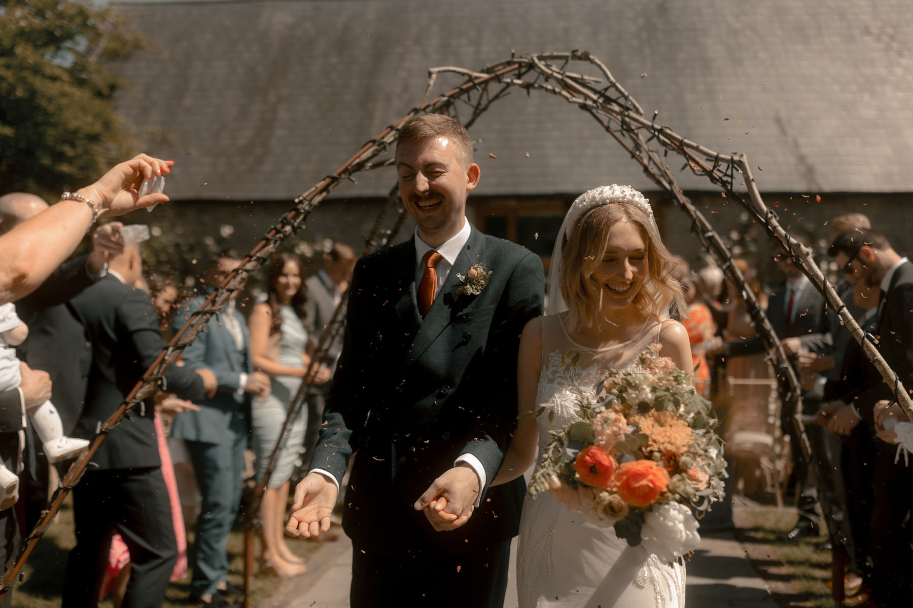 Outdoor wedding at Wick Farm, Bath. Bride carries a bright & colourful bouquet in whites and oranges.