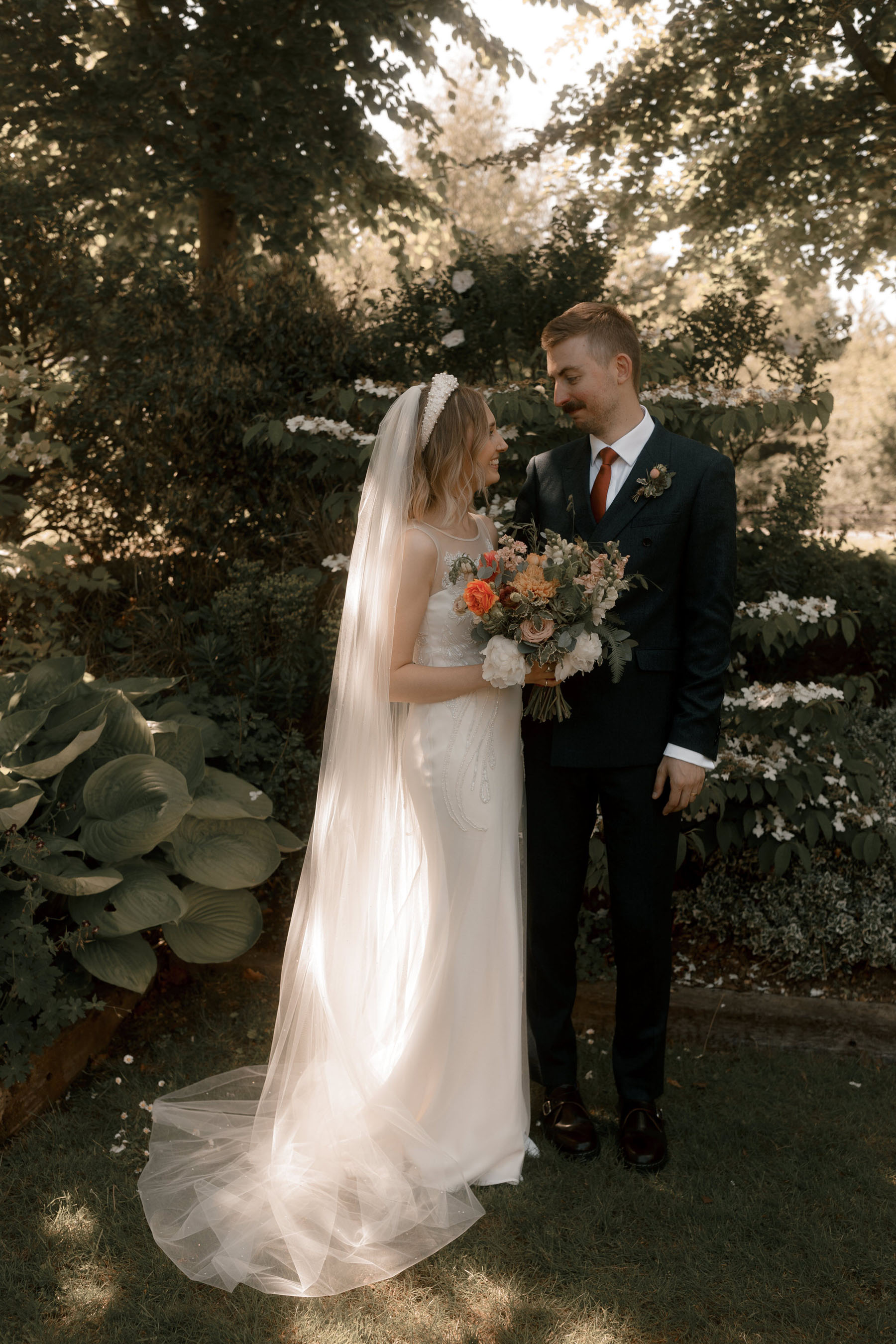 Bride in David Fielden wedding dress, pearl headband and orange bouquet. Groom in dark suit & tie.