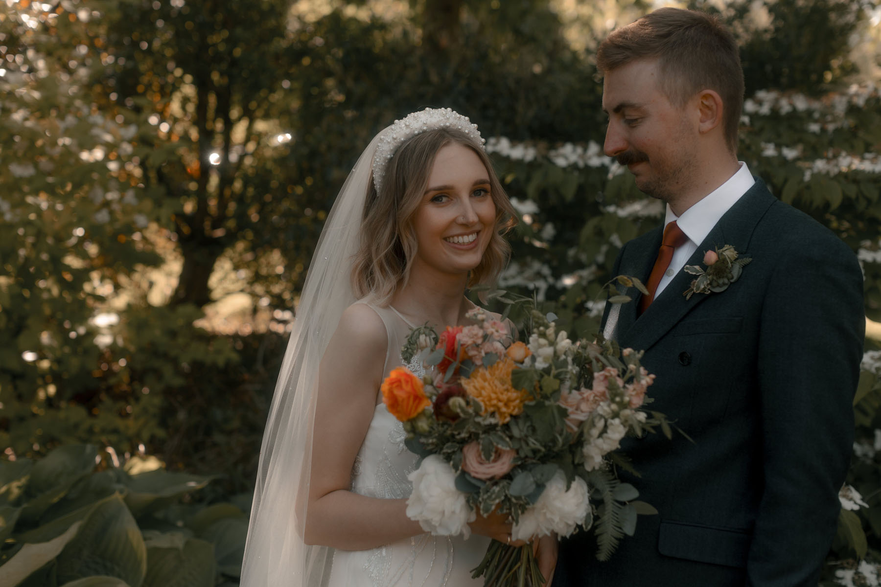 Bride in David Fielden wedding dress & pearl headband, carrying an orange wedding bouquet.