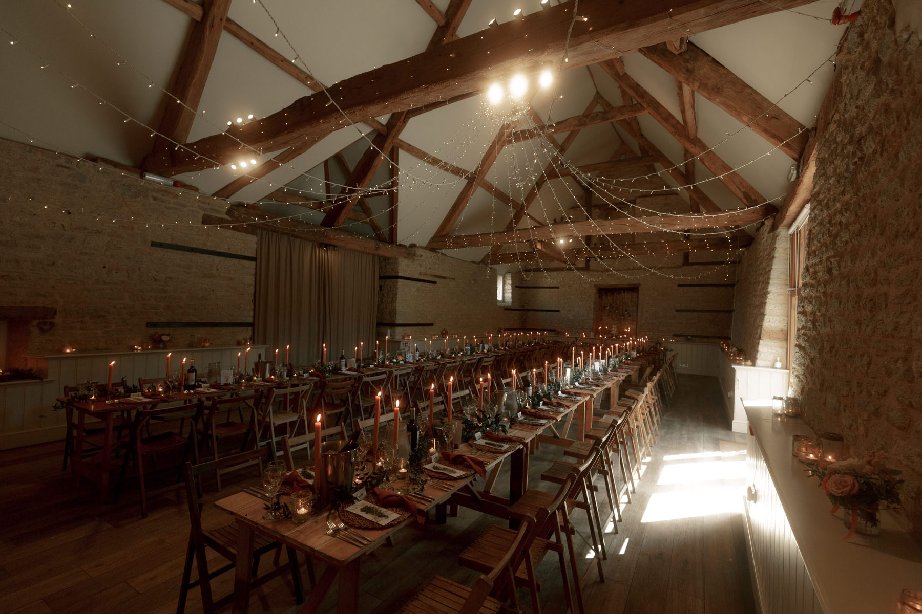 Wick farm barn wedding venue, Bath. Beamed barn reception room with wooden trestle tables.