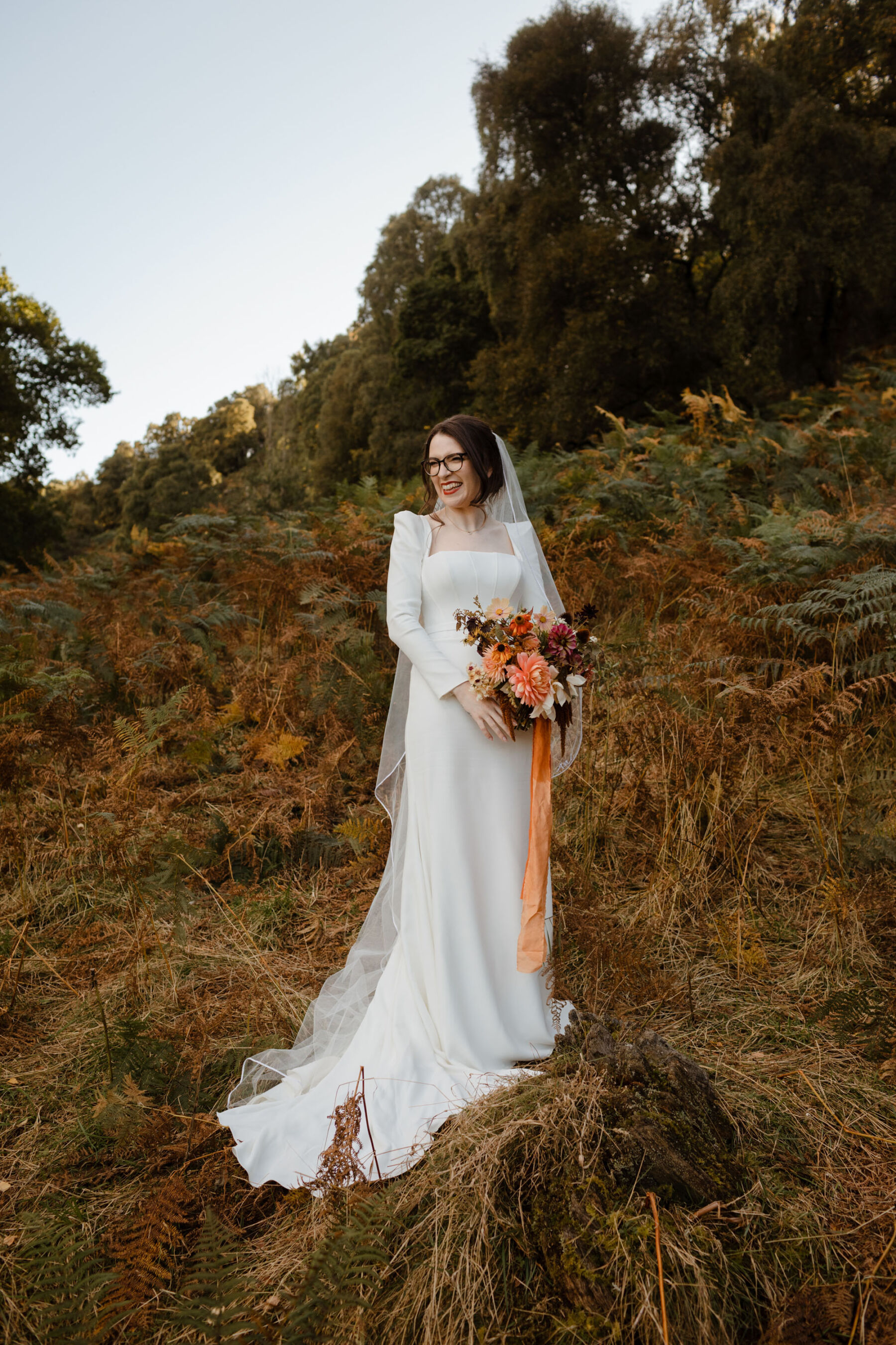 Bride in Amber by Suzanne Neville carrying a Colourful Autumn Dahlia wedding bouquet