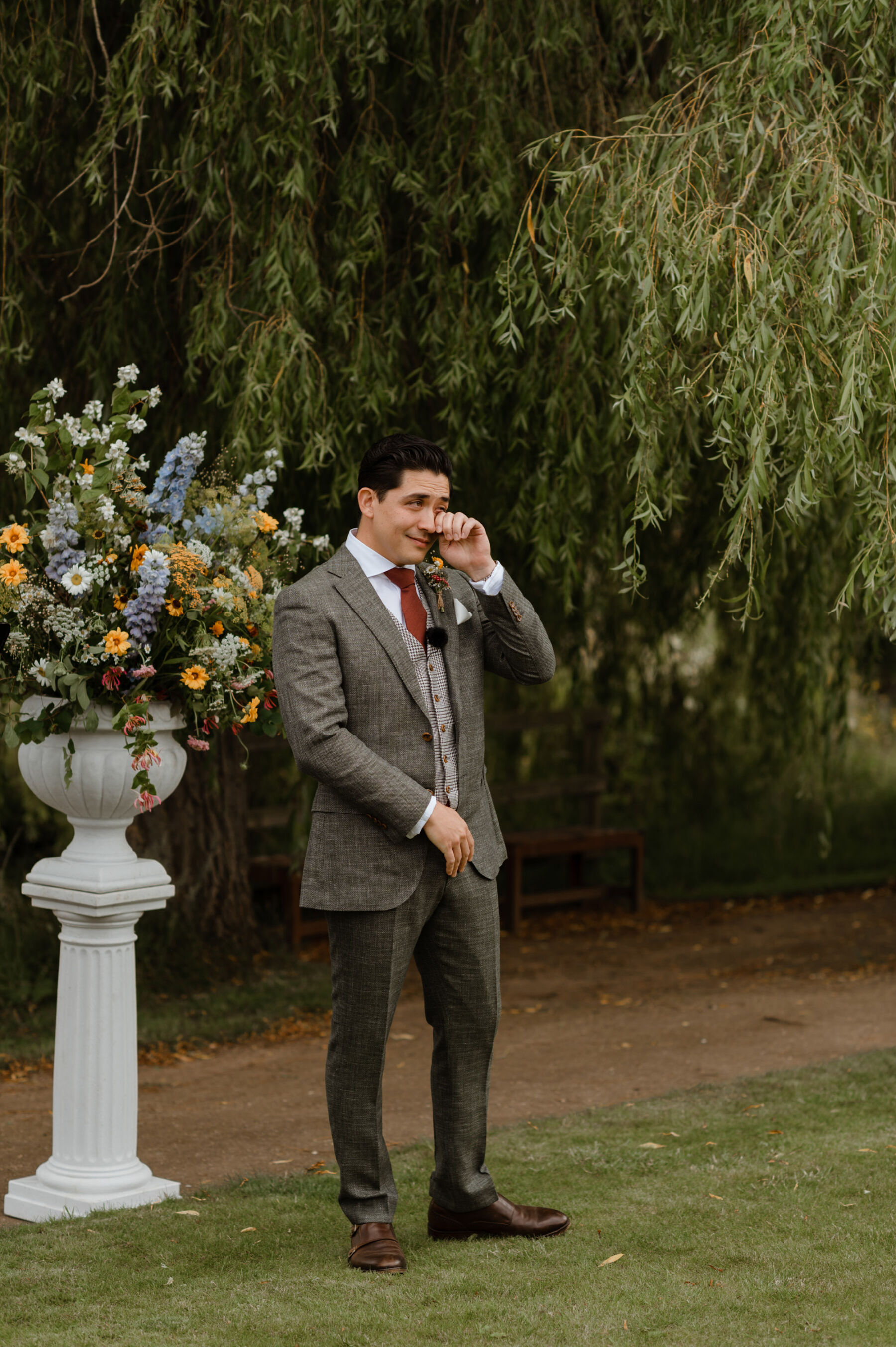 Groom wiping away tears as he watches his bride walk down the aisle