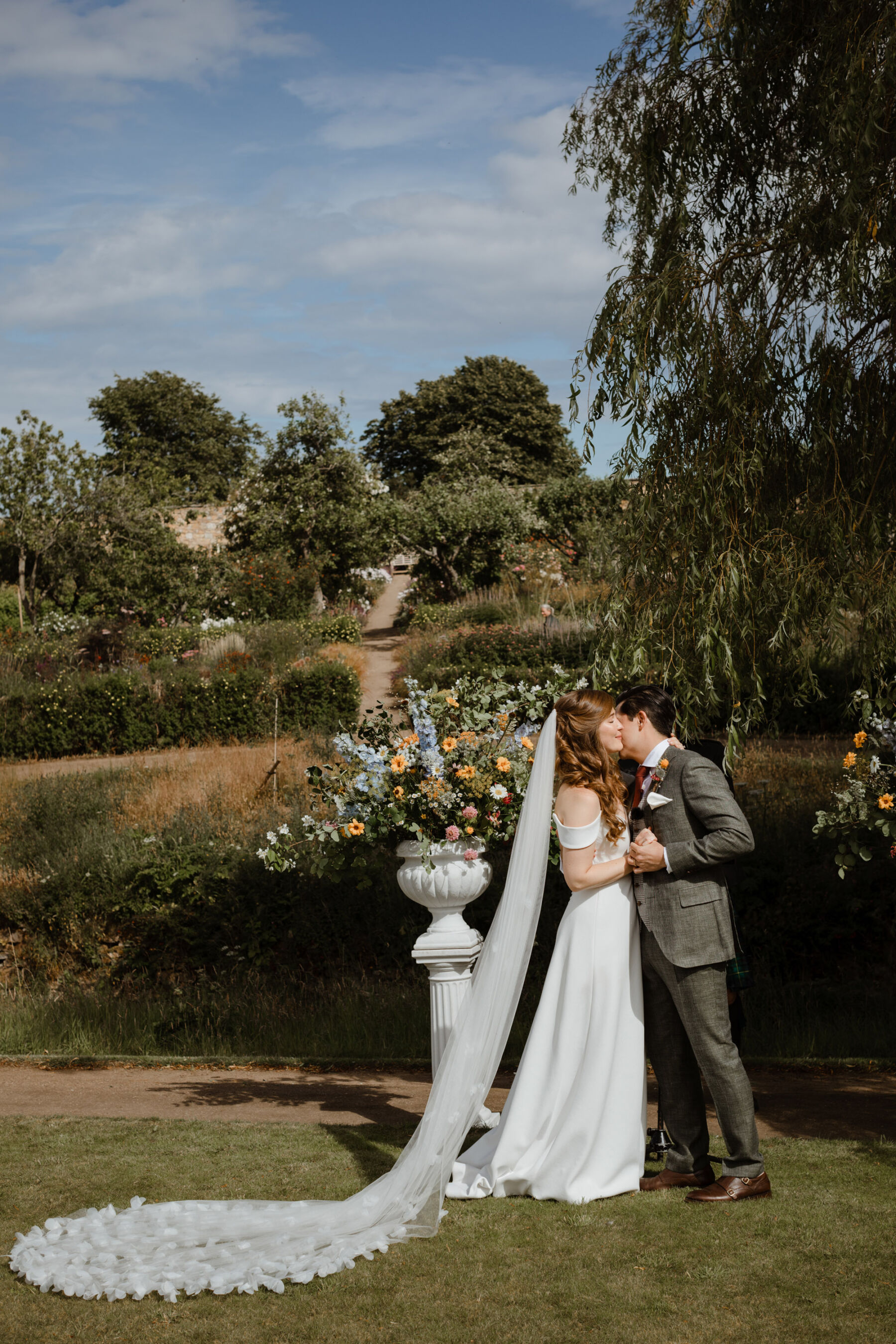 Bride & groom kissing in outdoor wedding ceremony at Cambo Estate