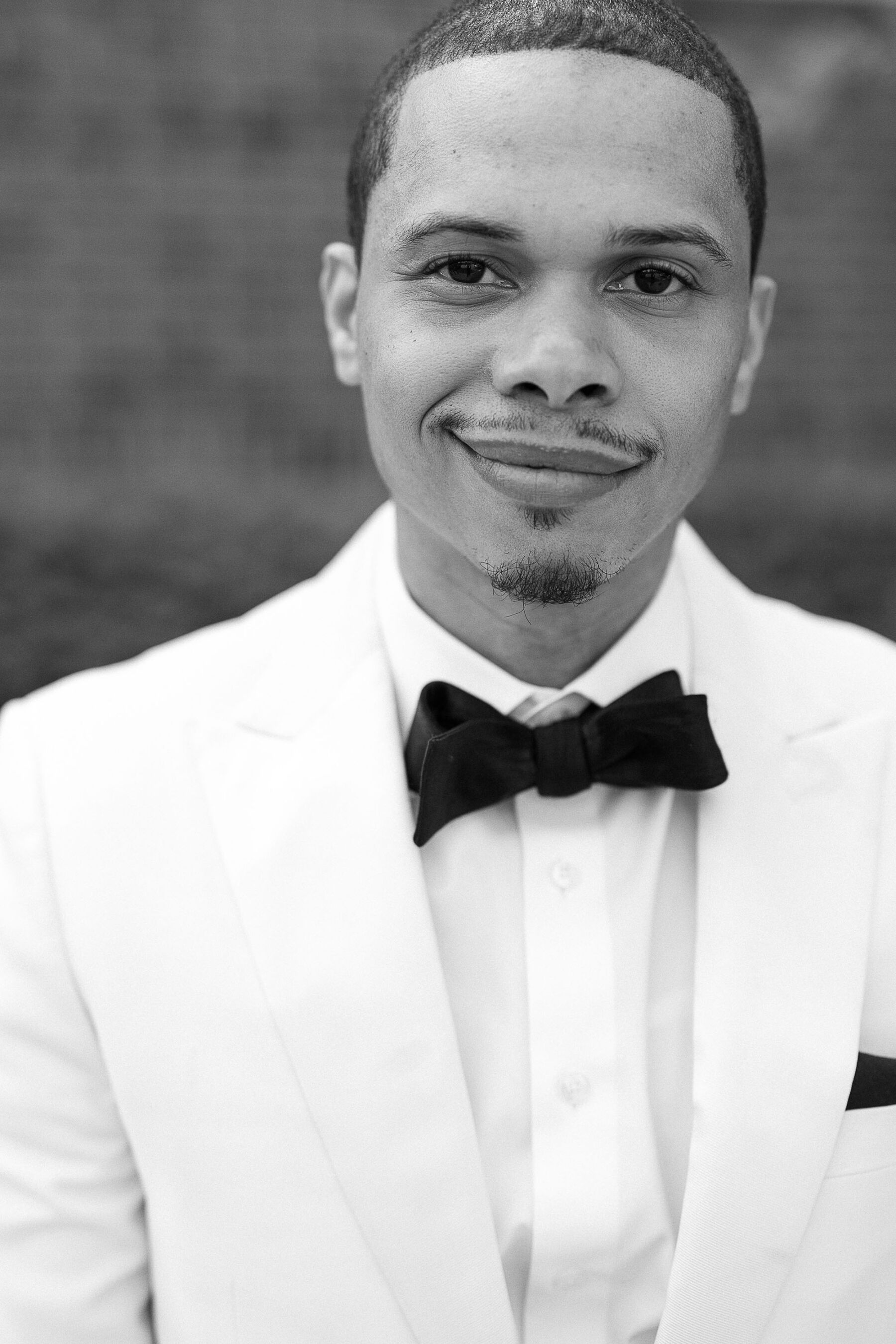 Portrait of black groom in a white tuxedo