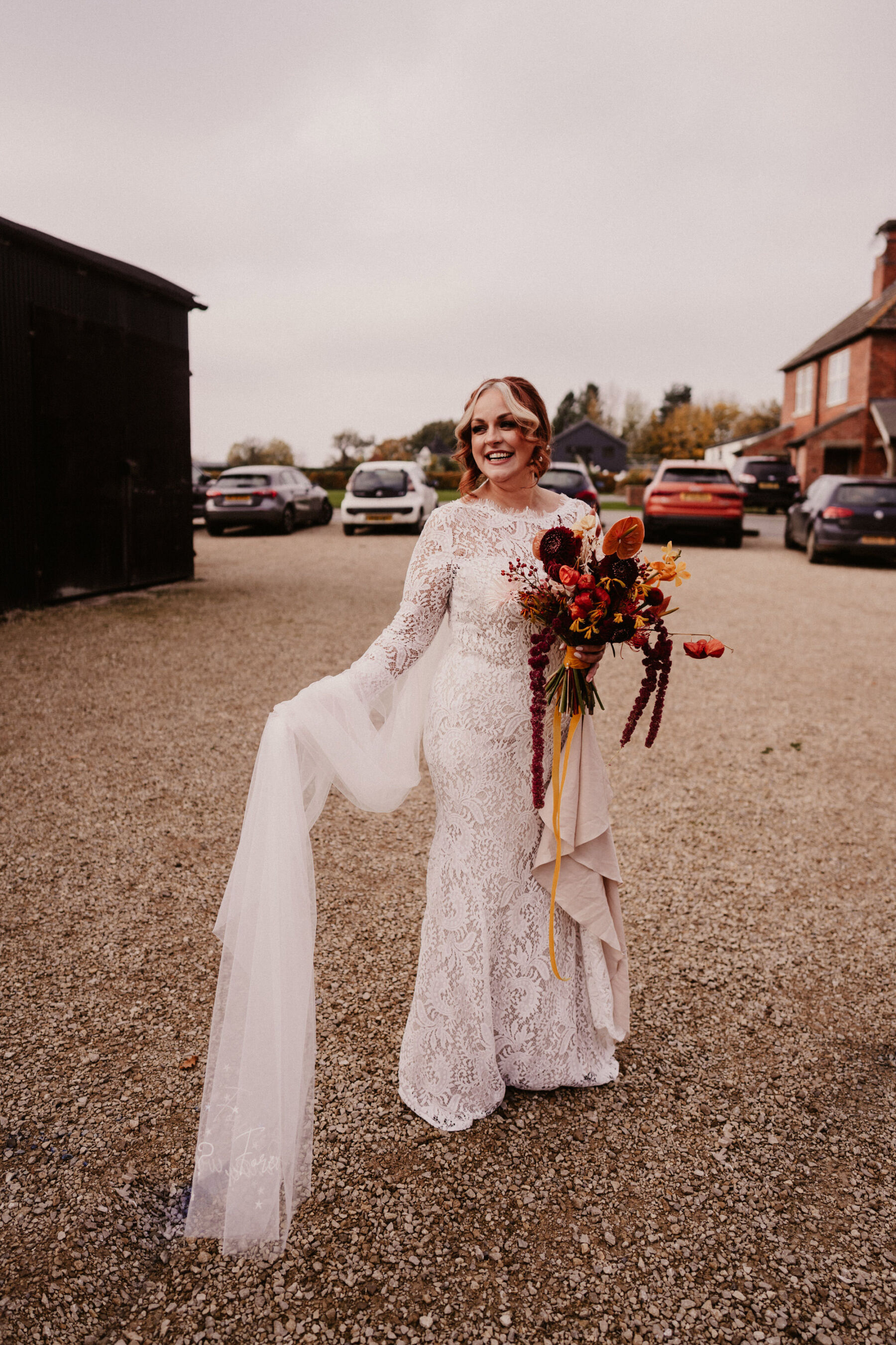 Wendy Makin lace dress. Bride carries a bold and colourful late Autumn wedding bouquet.