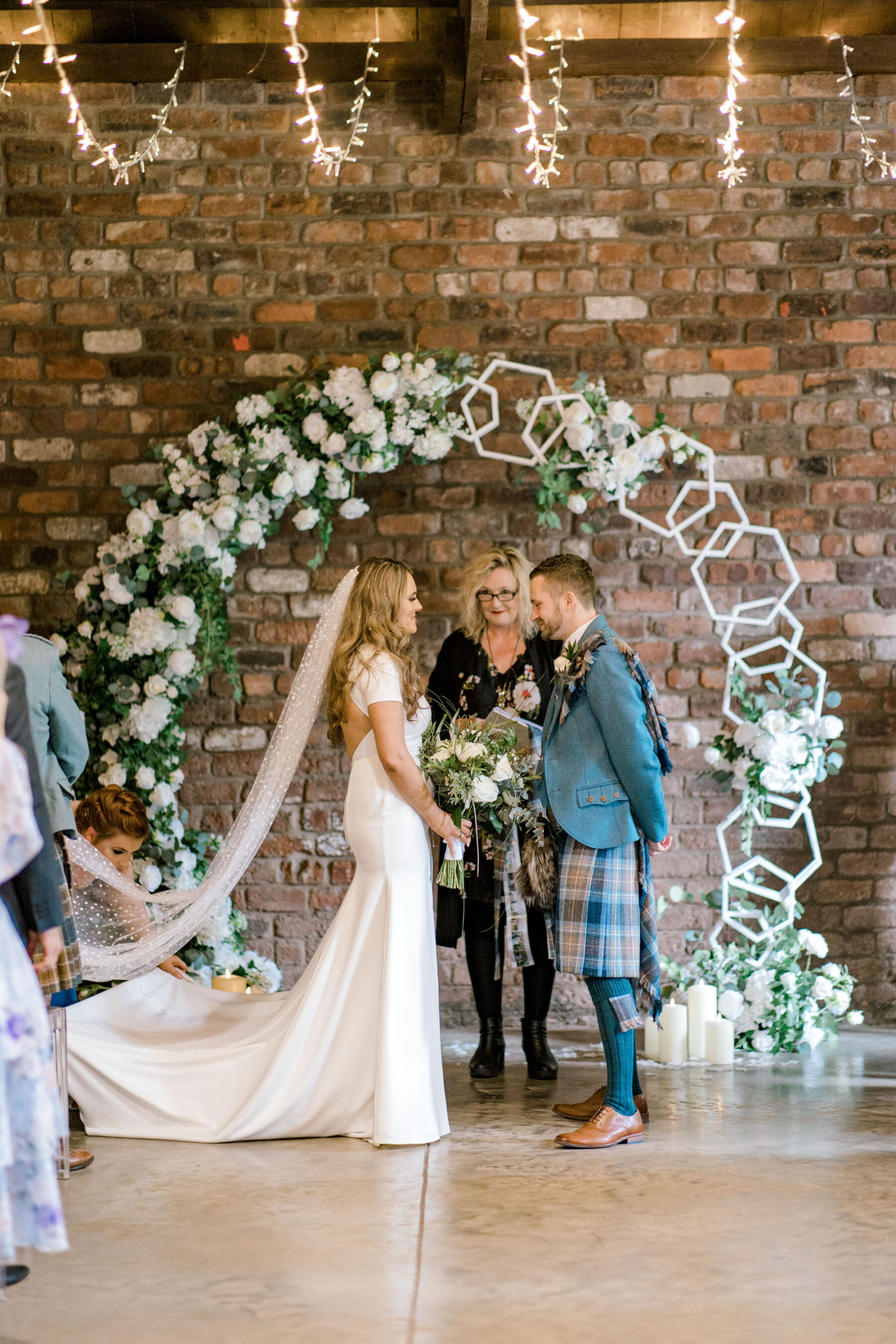 Bride and groom getting married by a floral arch at Glasgow Engine Works industrial wedding venue