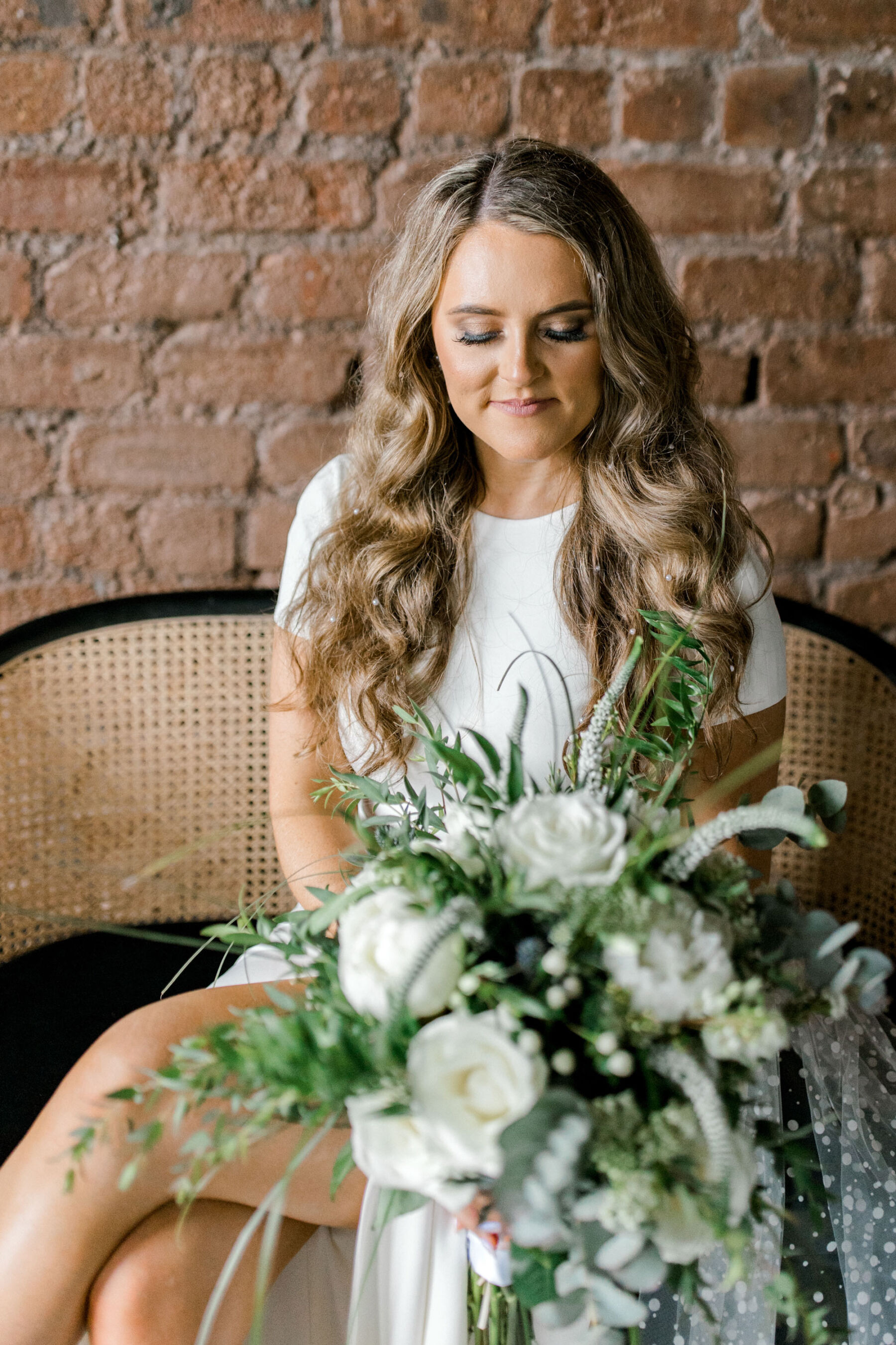 Bride with long blonde wavy hair and a large green and white bouquet