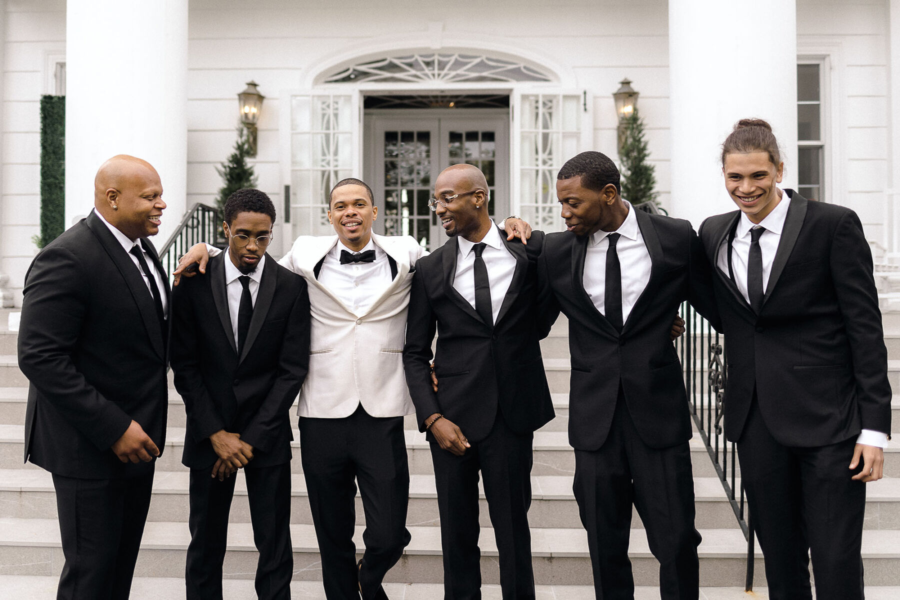 Black groom in white tuxedo and groomsmen in black tuxedo / black tie