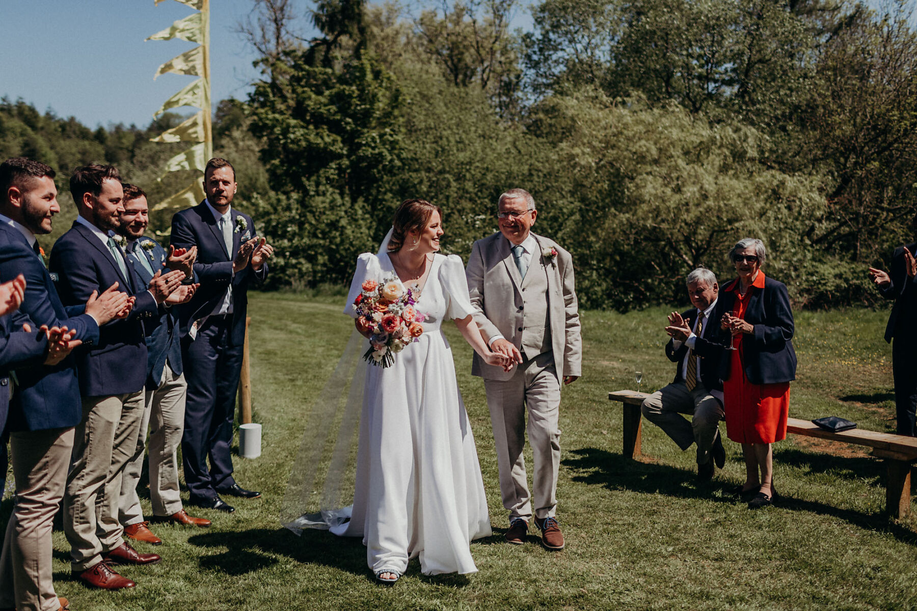 Father of the bride accompanying his daughter down the grassy aisle. Outdoor wedding at Hadsham farm.
