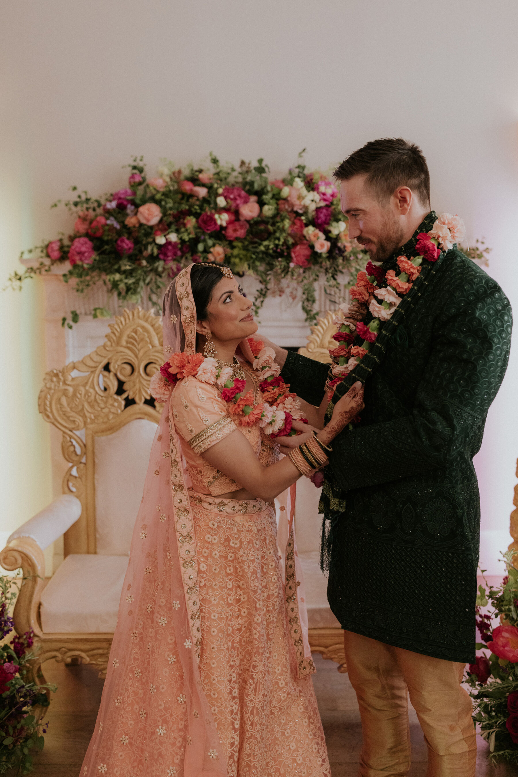 Indian bride at Hindu wedding ceremony in pink lehenga and floral garland