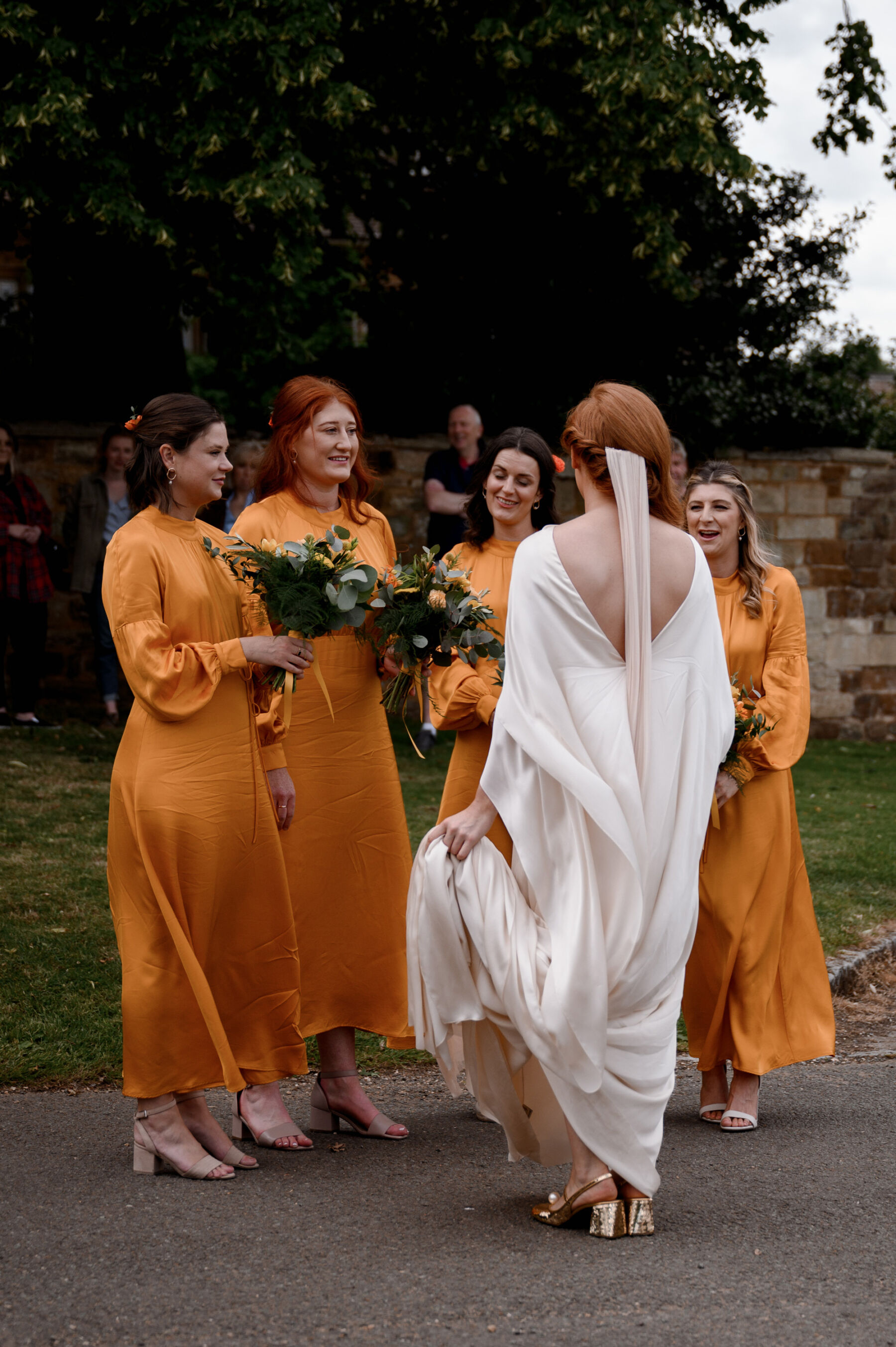 Bridesmaids in orange dresses. Bride wears Cortana dress and Miu Miu sequin shoes. Taylor Hughes Photography.