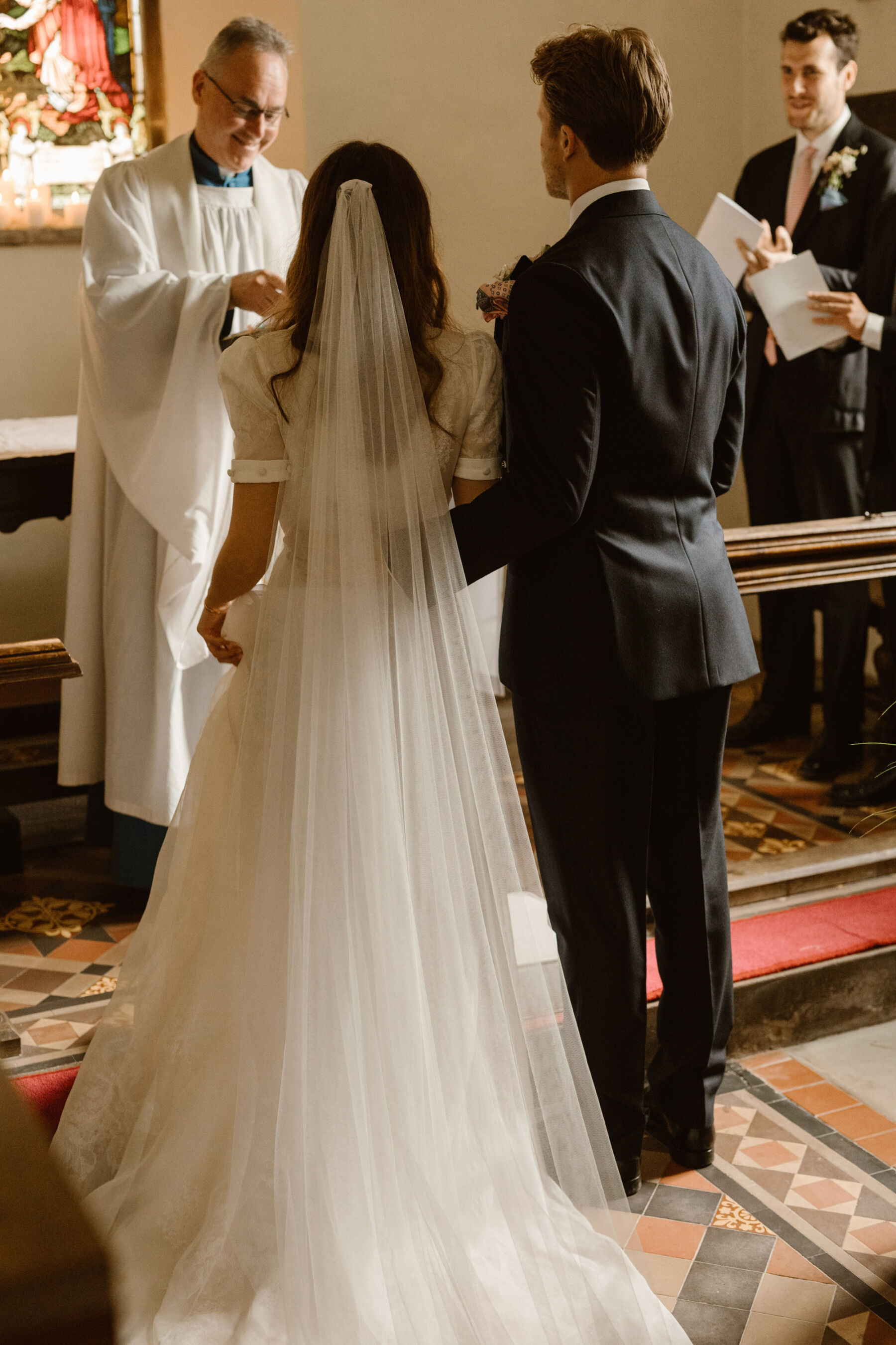 Wedding at Dewsall church, Herefordshire. Bride wears J Andreatta dress and long veil. Agnes Black Photography.