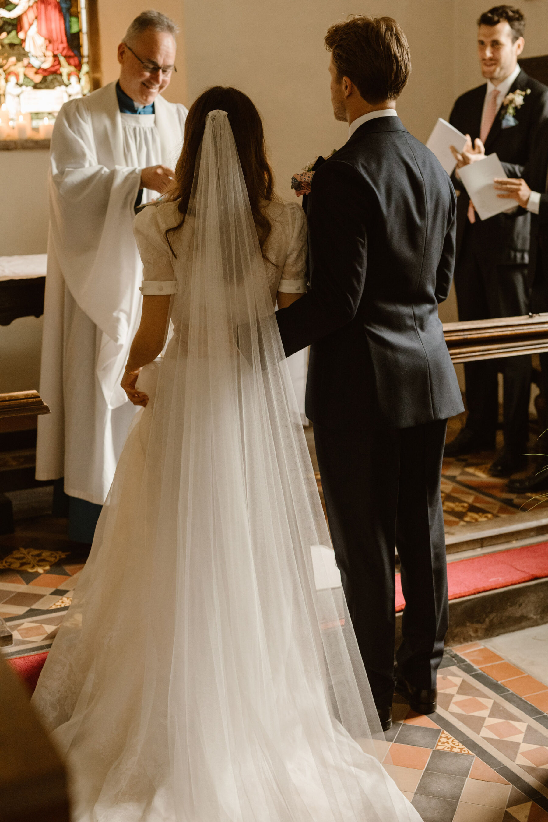 Jess in J. Andreatta for her Elegant Weekend Wedding at Dewsall Court 18 Wedding at Dewsall church, Herefordshire. Bride wears J Andreatta dress and long veil. Agnes Black Photography.