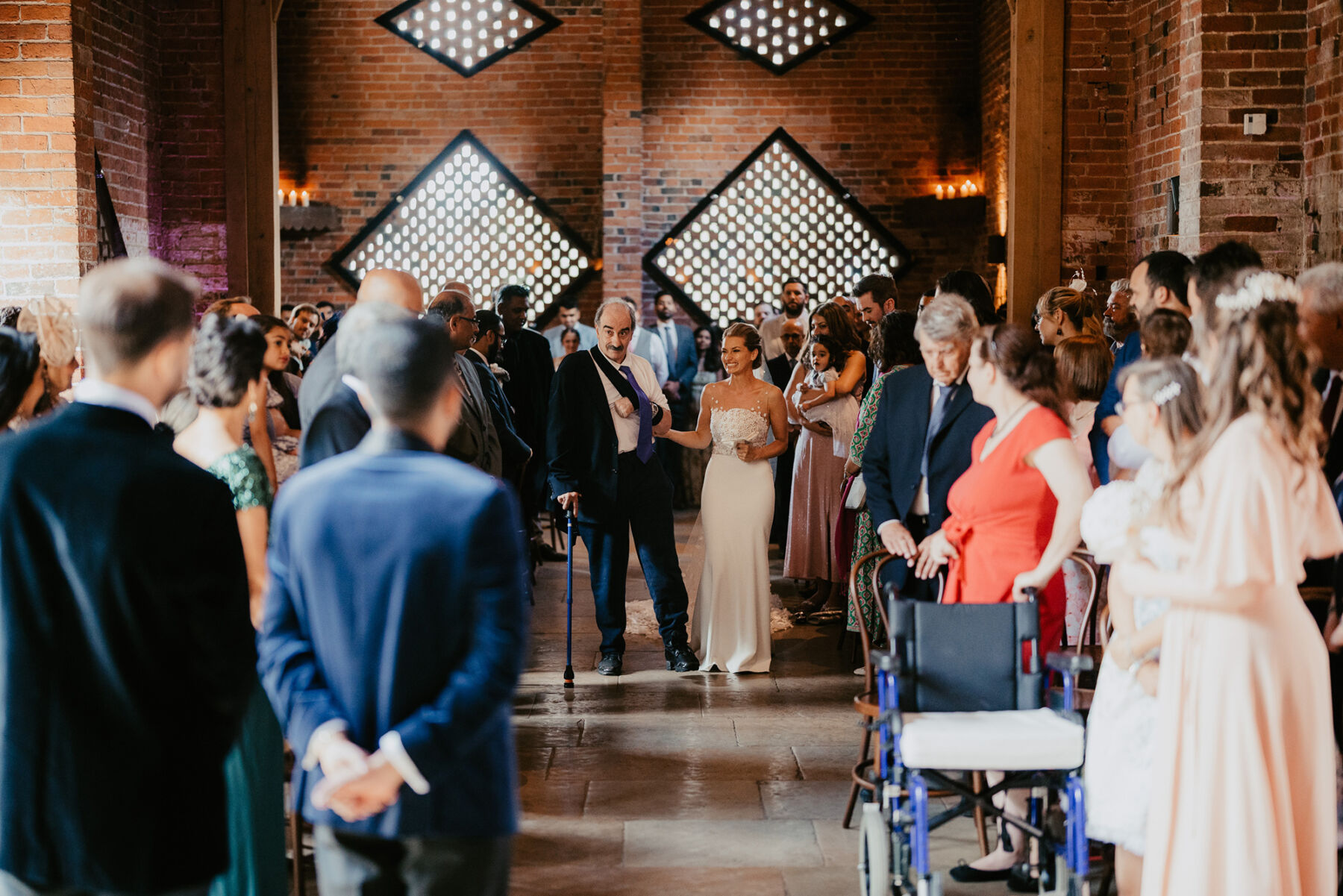 Elderly father with a walking stick, walking his daughter bride down the aisle at Shustoke Barn.