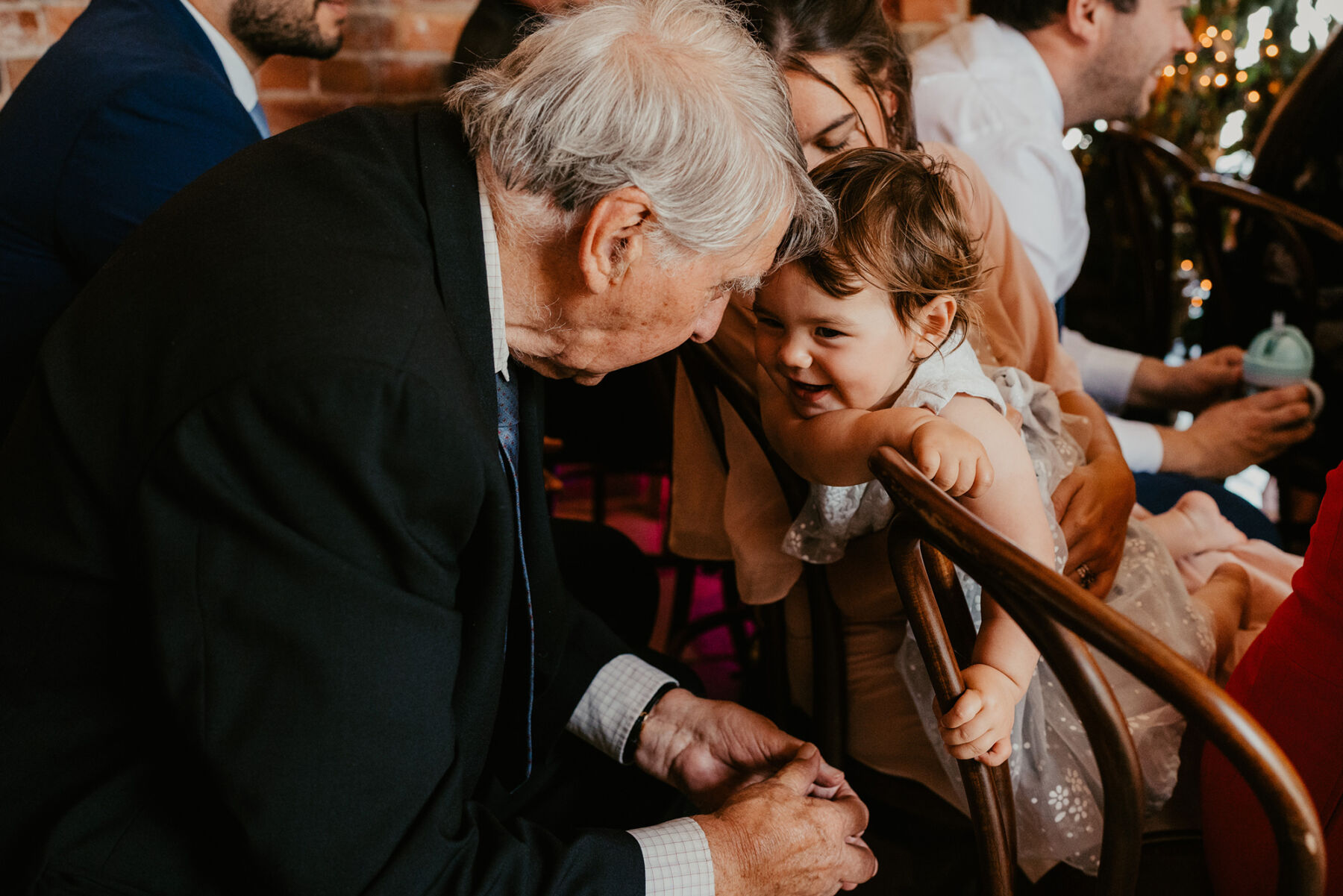 Elderly wedding guests bending forward to interact with baby wedding guest.