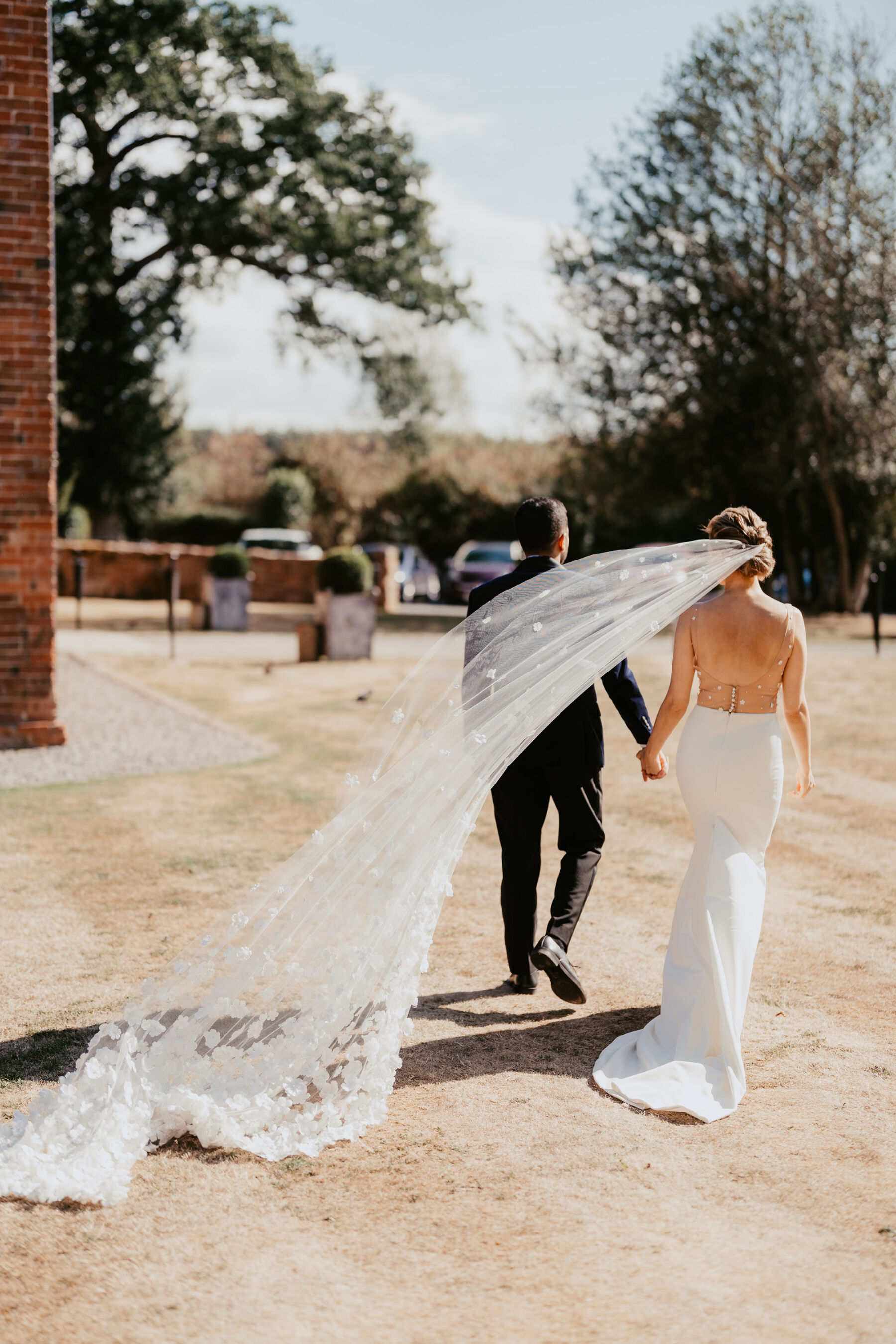 Bride with long, flyaway veil outside Shustoke Barn wedding venue.