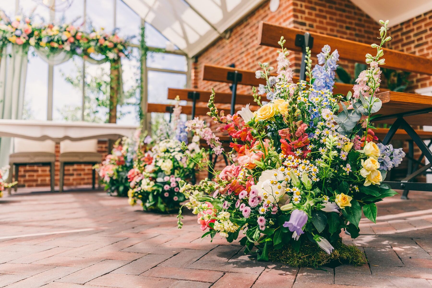 Eucalyptus Events, Cotswolds Wedding Planner. Bright and colourful flowers lining a wedding ceremony aisle.