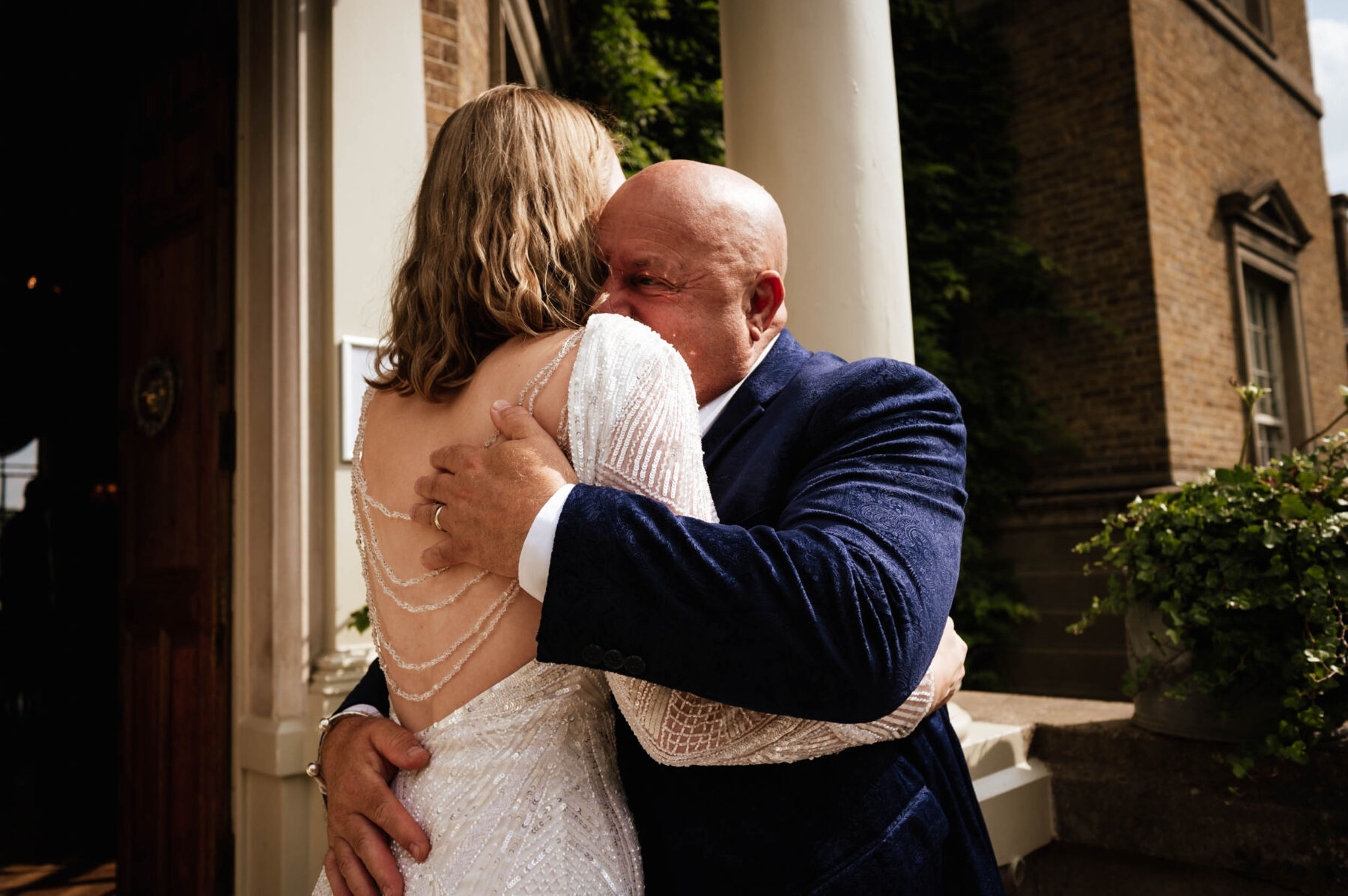 Father of the bride hugging his daughter who wears a backless Eliza Jane Howell wedding dress. Robin Goodlad Photography.