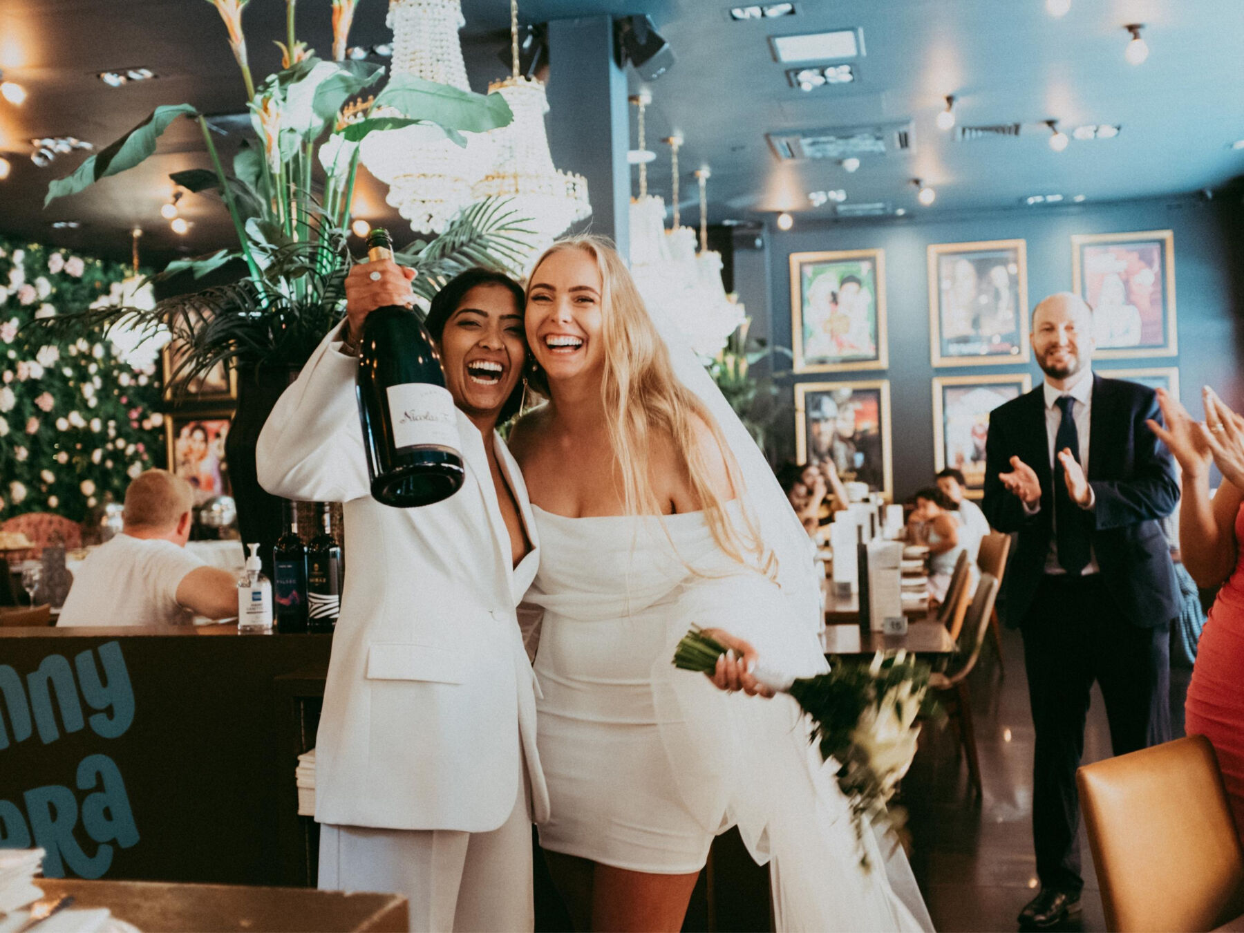 Lesbian brides at their same sex wedding with a bottle of champagne. Daniel Mice Photography.