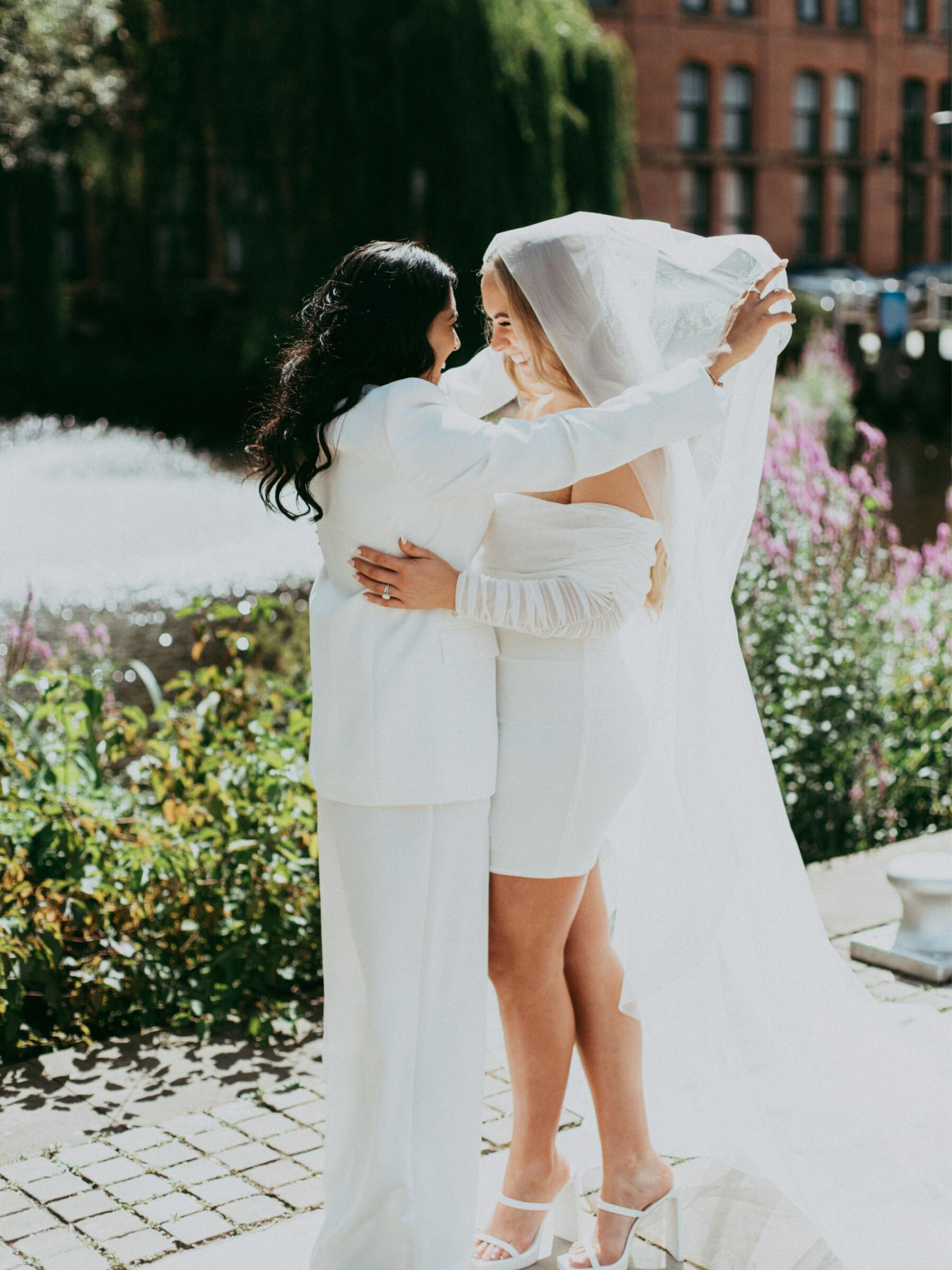 Lesbian bride in a suit lifting the veil on her Lesbian bride in a short dress. Daniel Mice Photography.