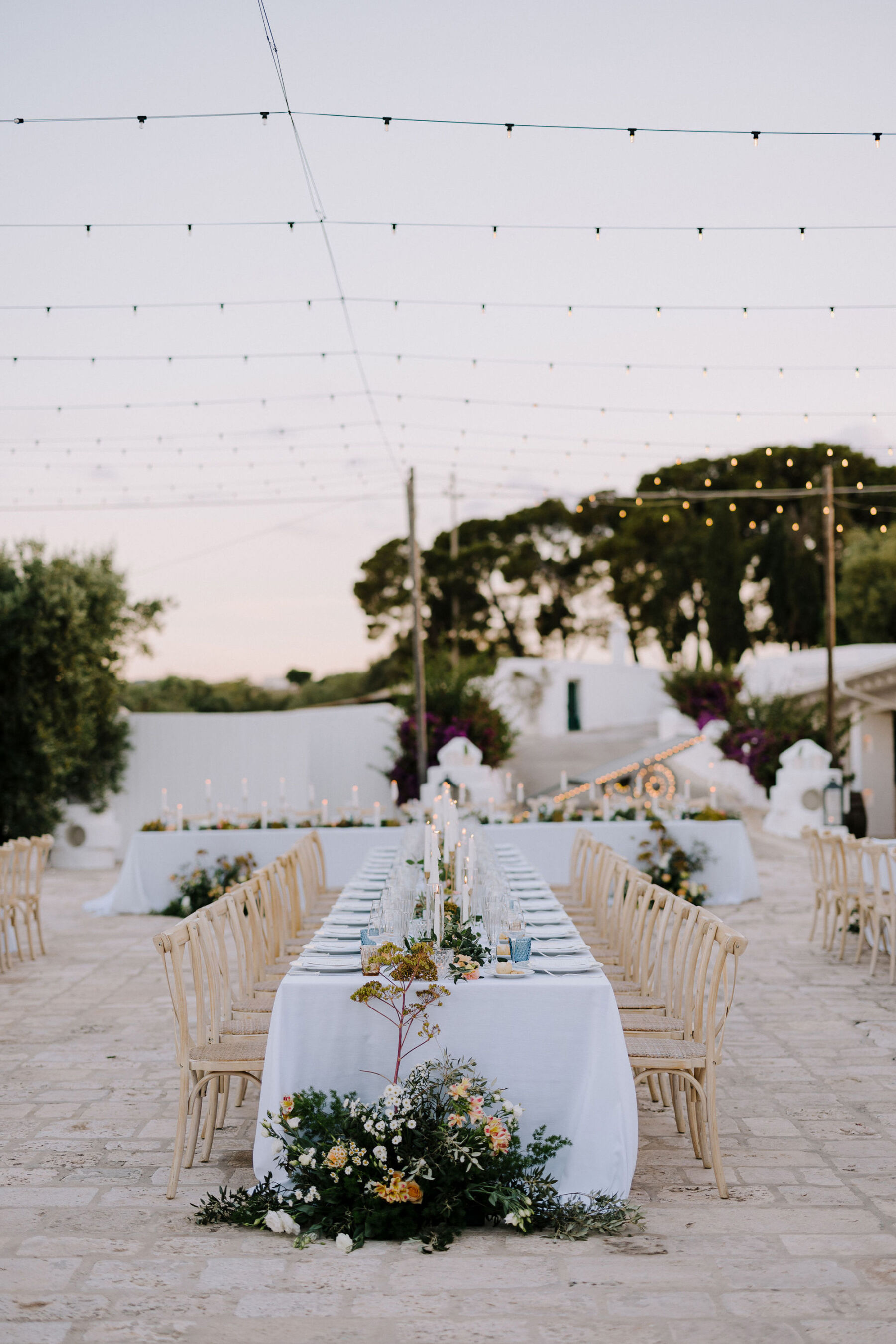 Beautiful table setting at an Italian villa wedding. Canopy of festoon lights.
