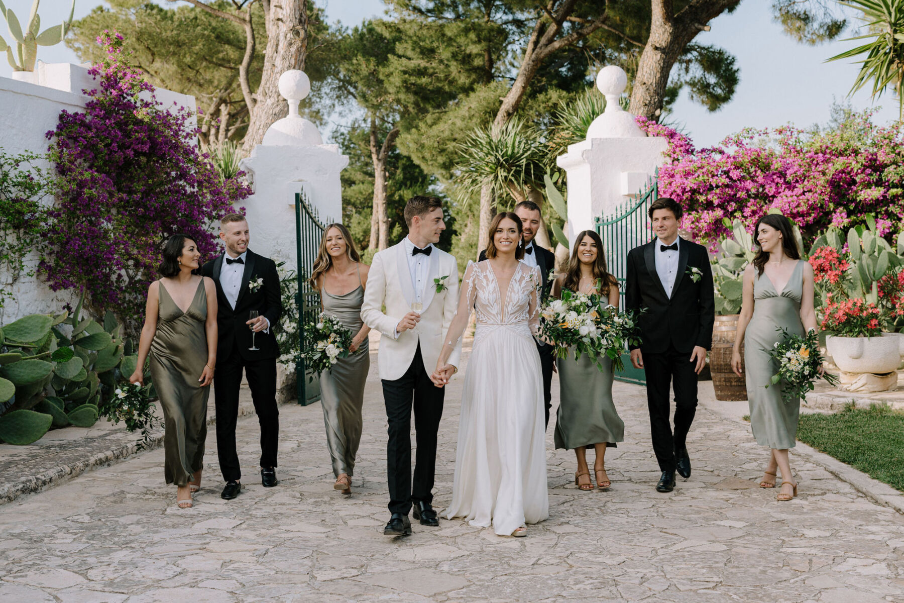 Black tie wedding party at an Italian villa wedding. Groom in white tuxedo. Bridesmaids in sage green dresses. Bride in Margaux Tardits wedding dress.