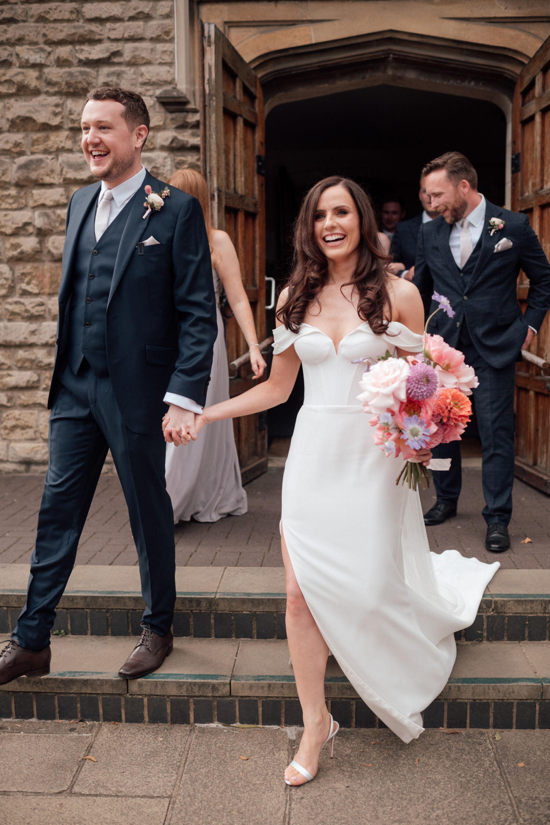 Bride in Roxy by Suzanne Neville - wedding dress with thigh slit. Bride carries large, bright and bold bouquet by BUD Flora. The Shannons Phtoography.