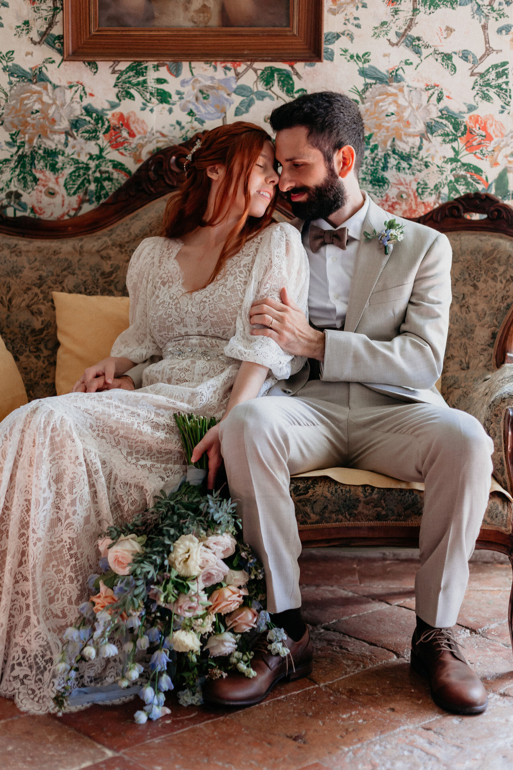 Bride wearing vintage inspired lace wedding dress by Katya Katya London. Groom in pale brown suit and brown bow tie. Italian wedding.