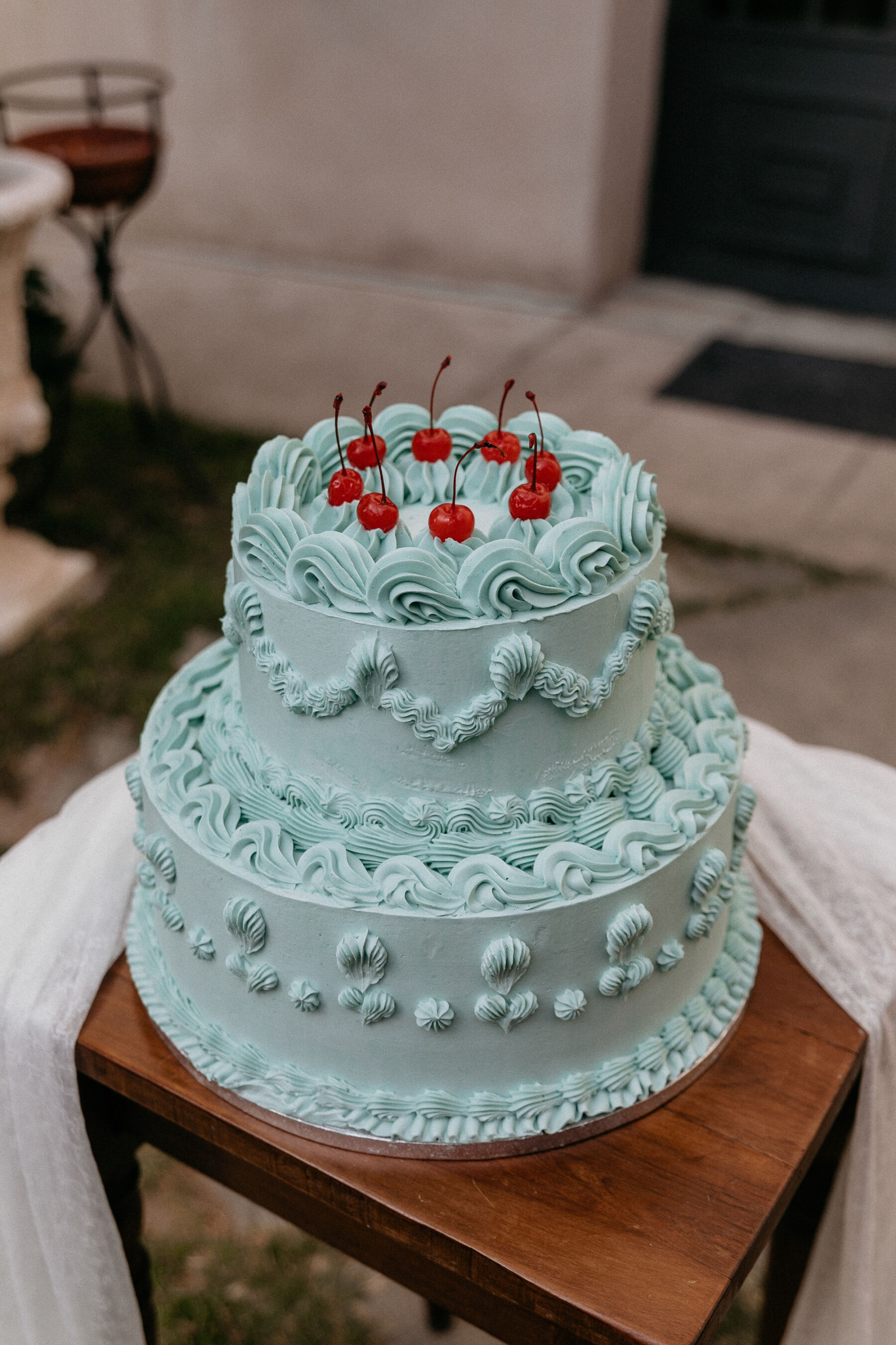 Fancy blue iced wedding cake topped with cherries.