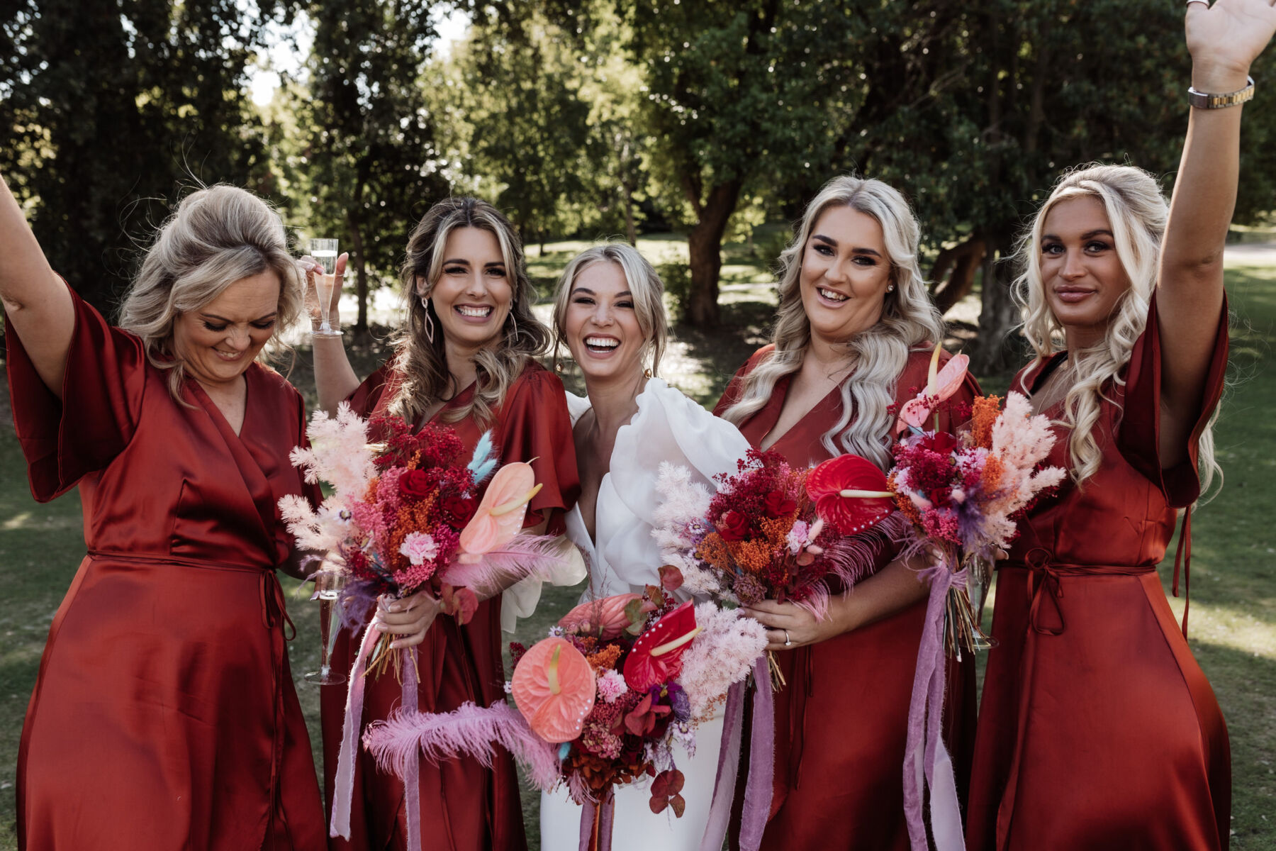 Bridesmaids in burnt orange dresses from Rewritten Bridesmaids, carrying vibrant and colourful wedding bouquets with dyed ferns and foliage. Alexandria French Photography.