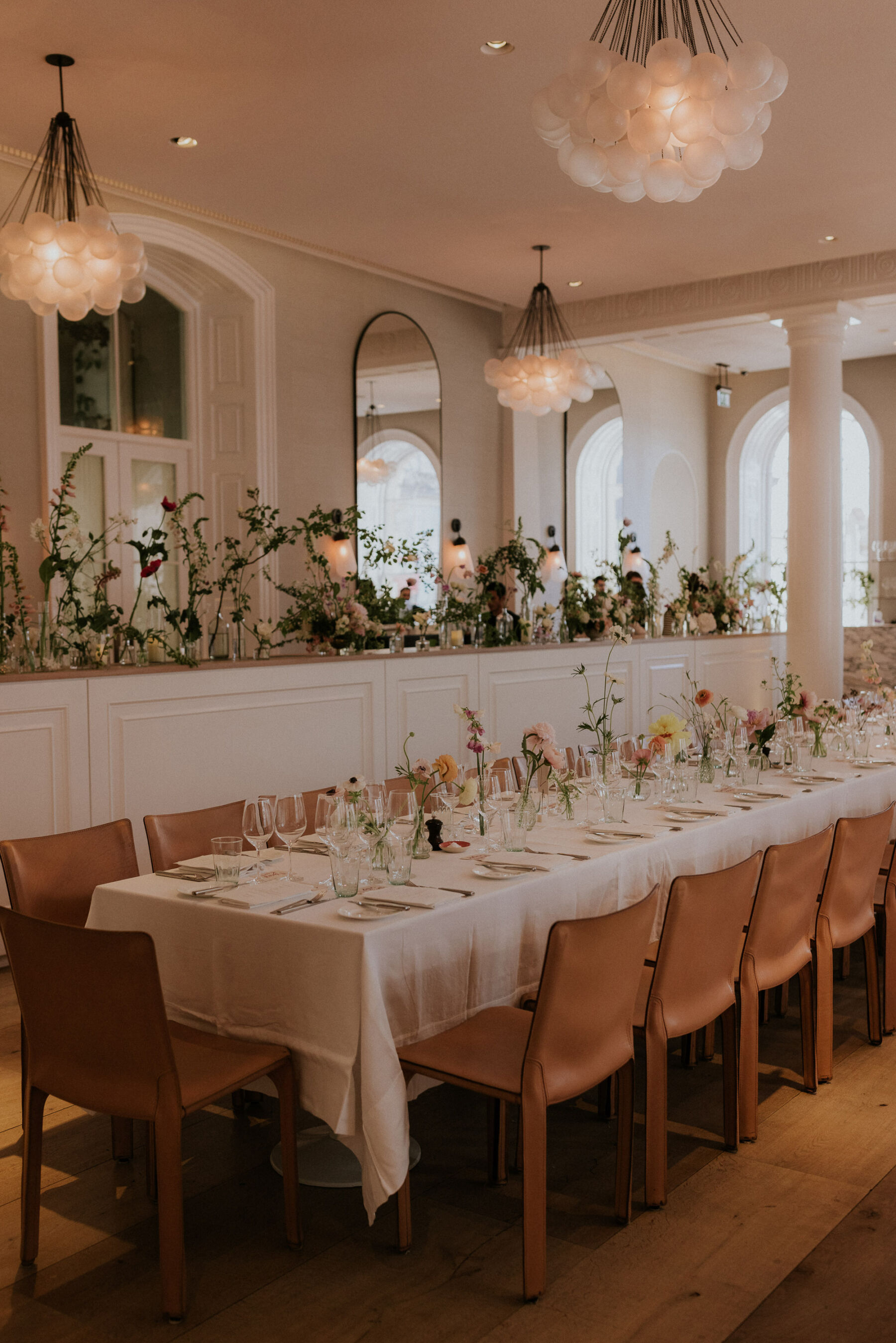 Spring Restaurant wedding table settings. Tables lined with simple spring flowers in bud bases.