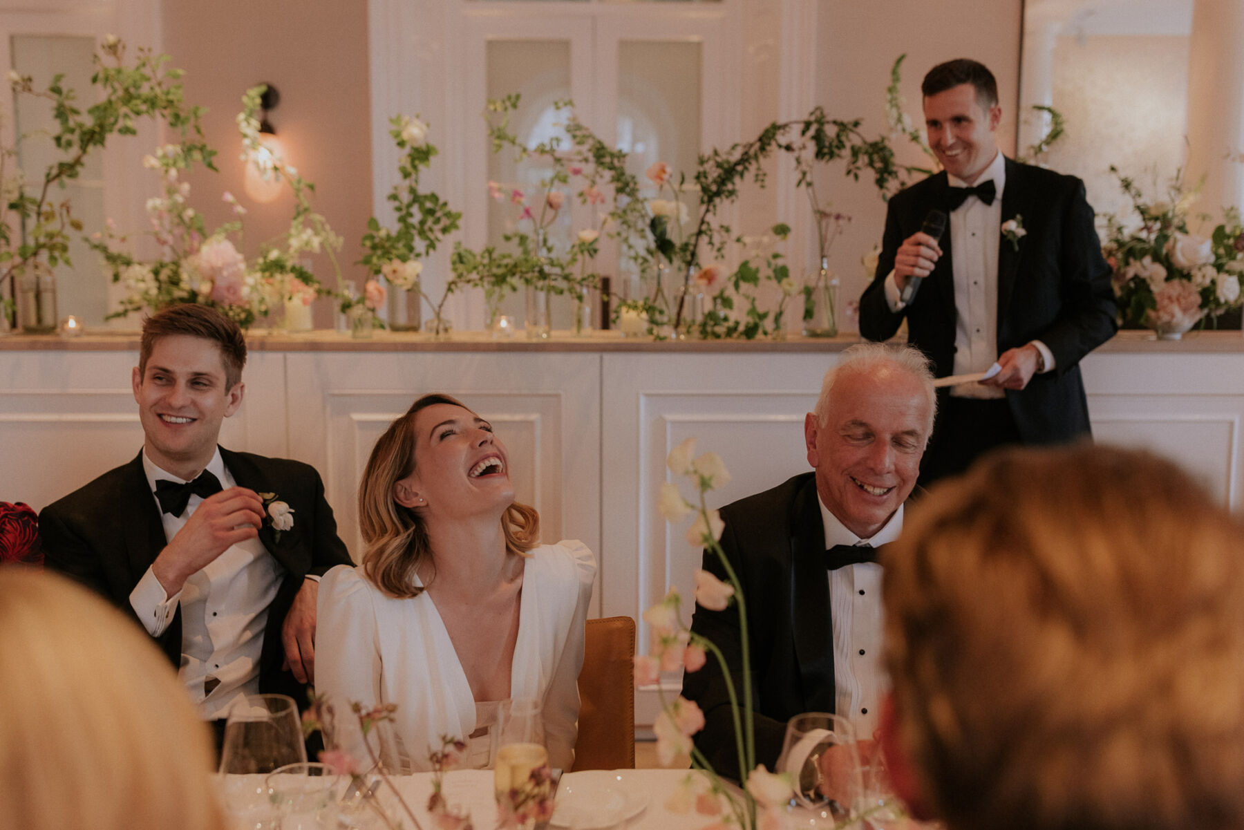 Bride laughing at the wedding reception table next to her dad. Maja Tsolo Photography.