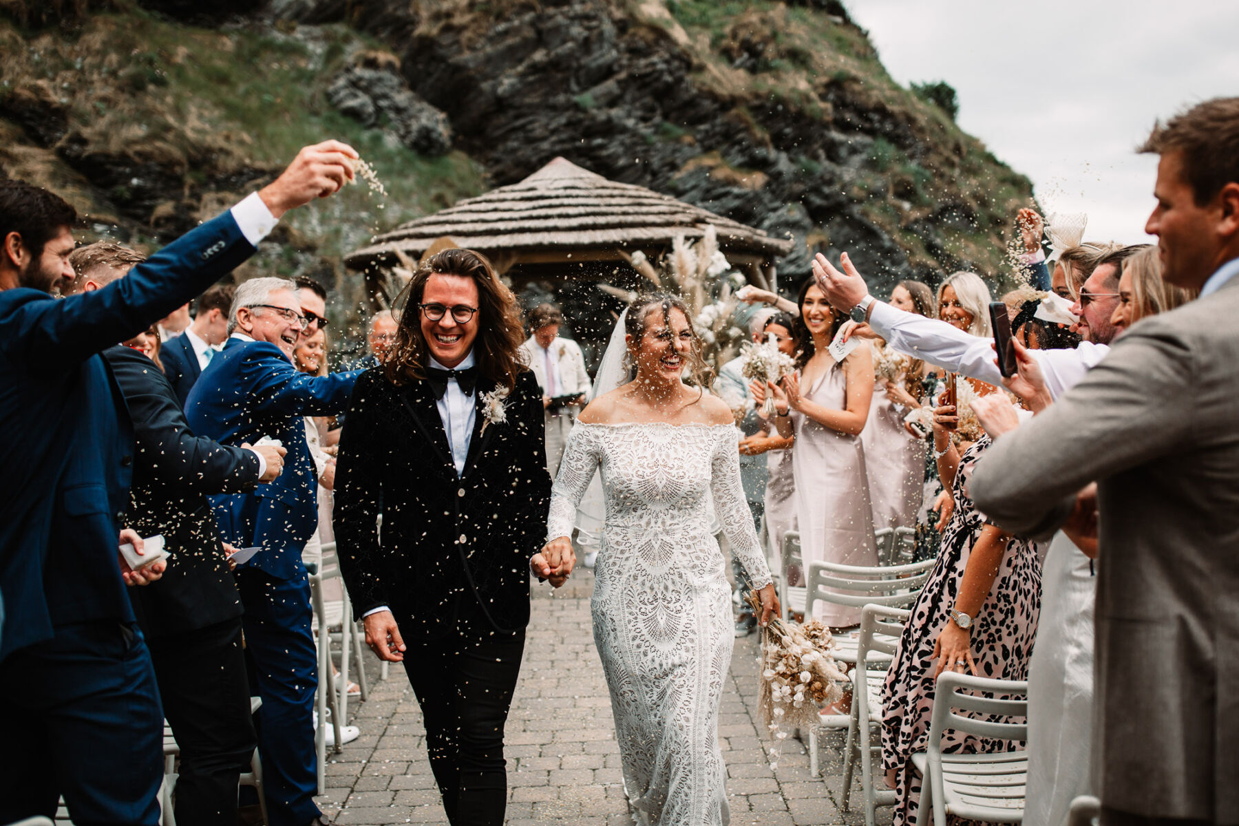 Confetti being thrown over a bride and groom at Tunnels Beaches in Devon. Bride wears Grace Loves Lace wedding dress.