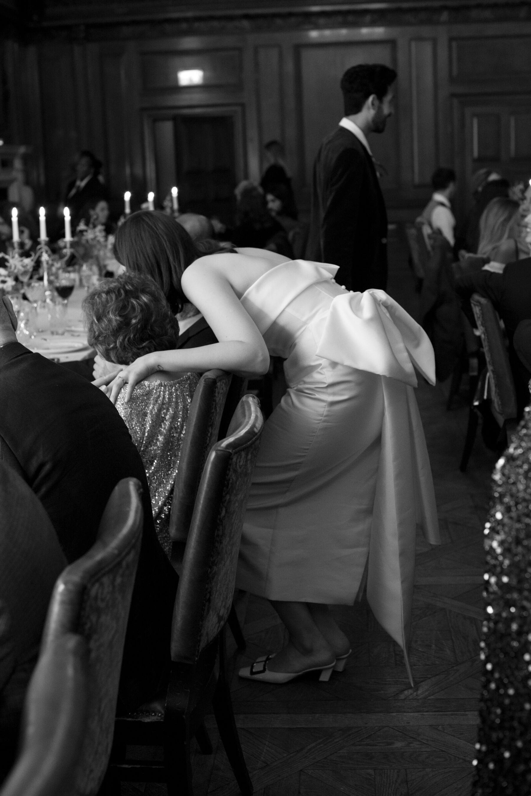 Bride bending down to talk to her guests who seated at the reception