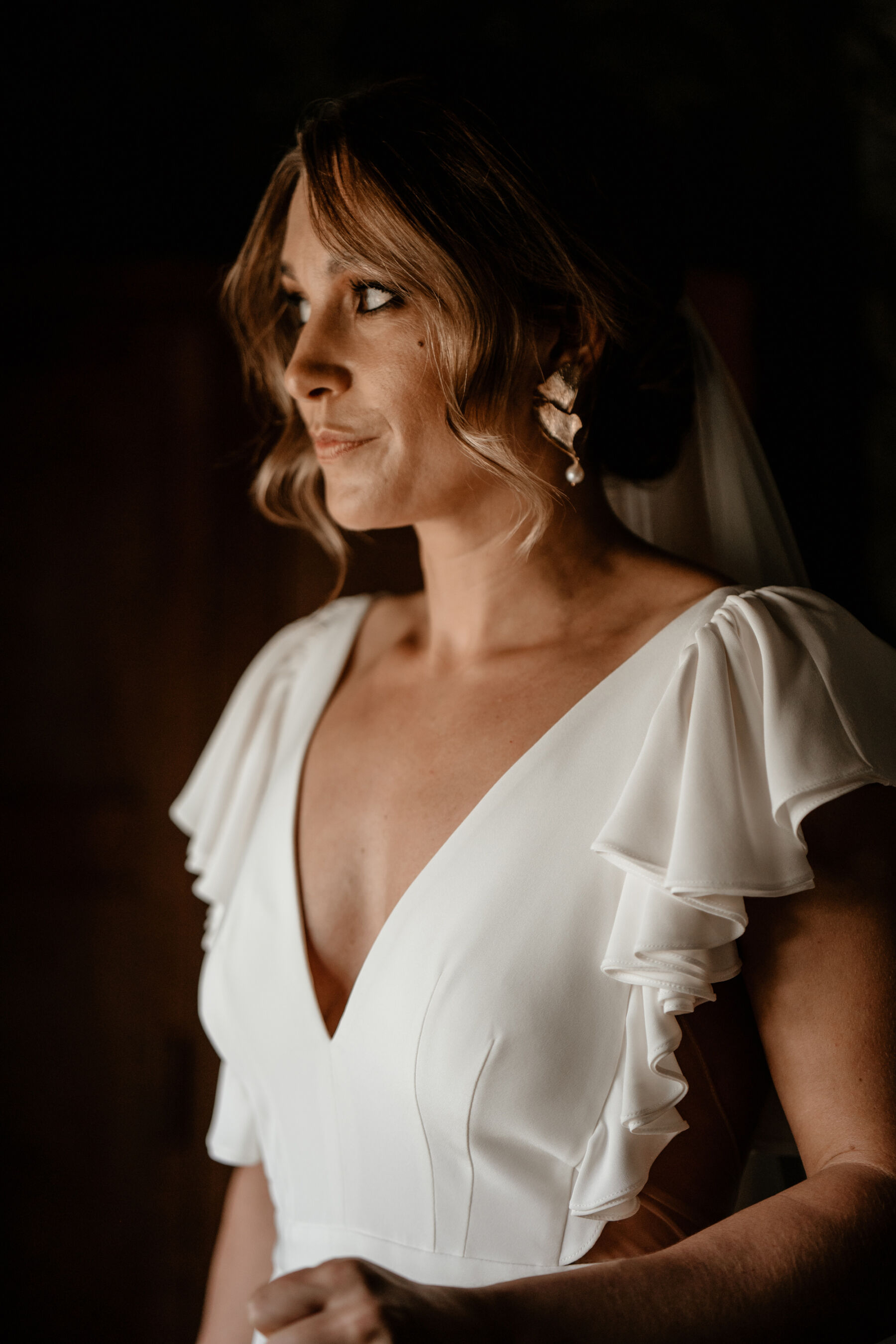 Bride in Alexander Grecco wedding dress and modern gold earrings