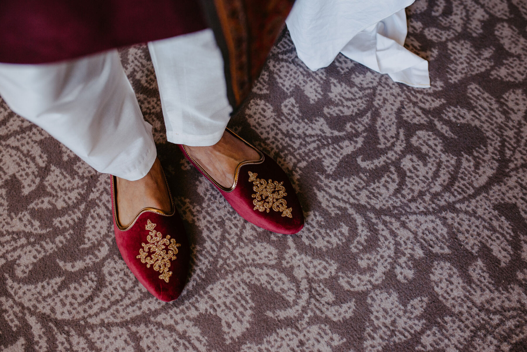 Asian groom in pointed red shoes.