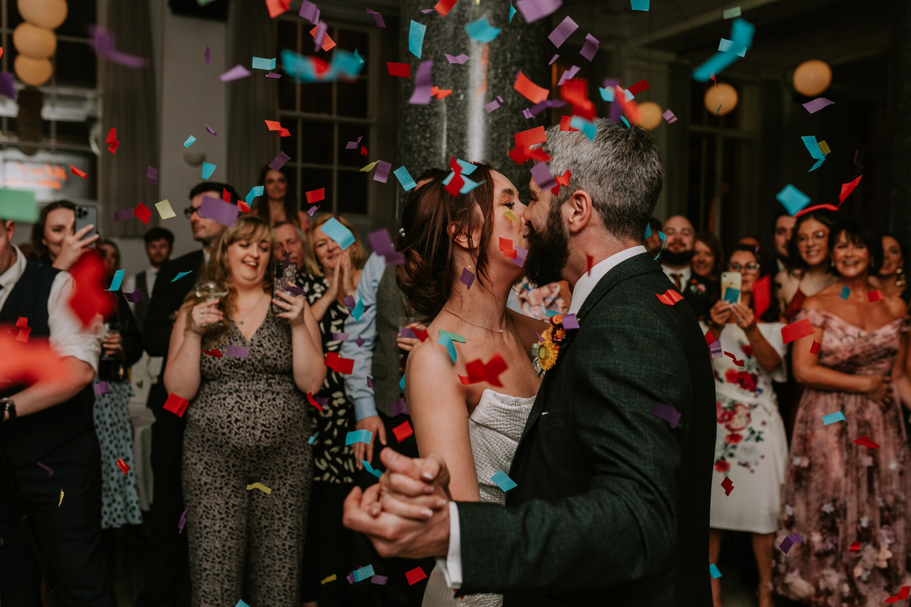 Bride and groom getting showered with colourful confetti whilst on the dance floor.