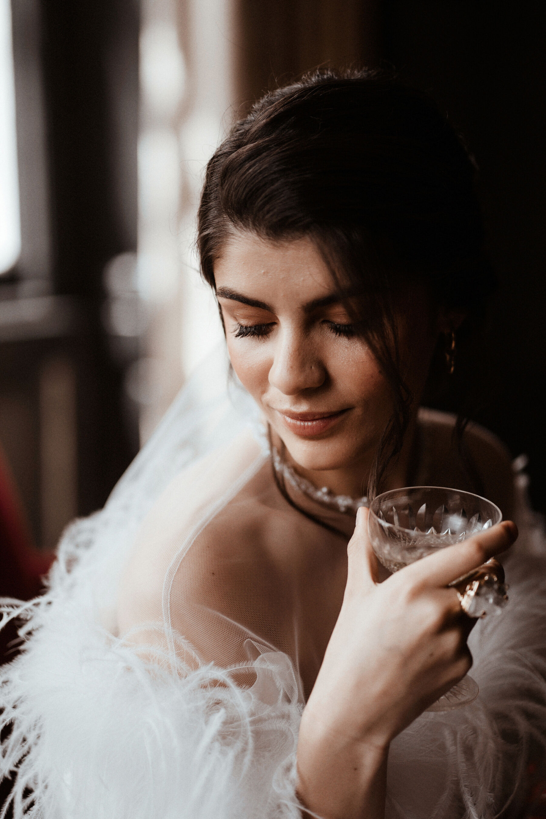 Bride looking romantically into a crystal cut champagne glass.