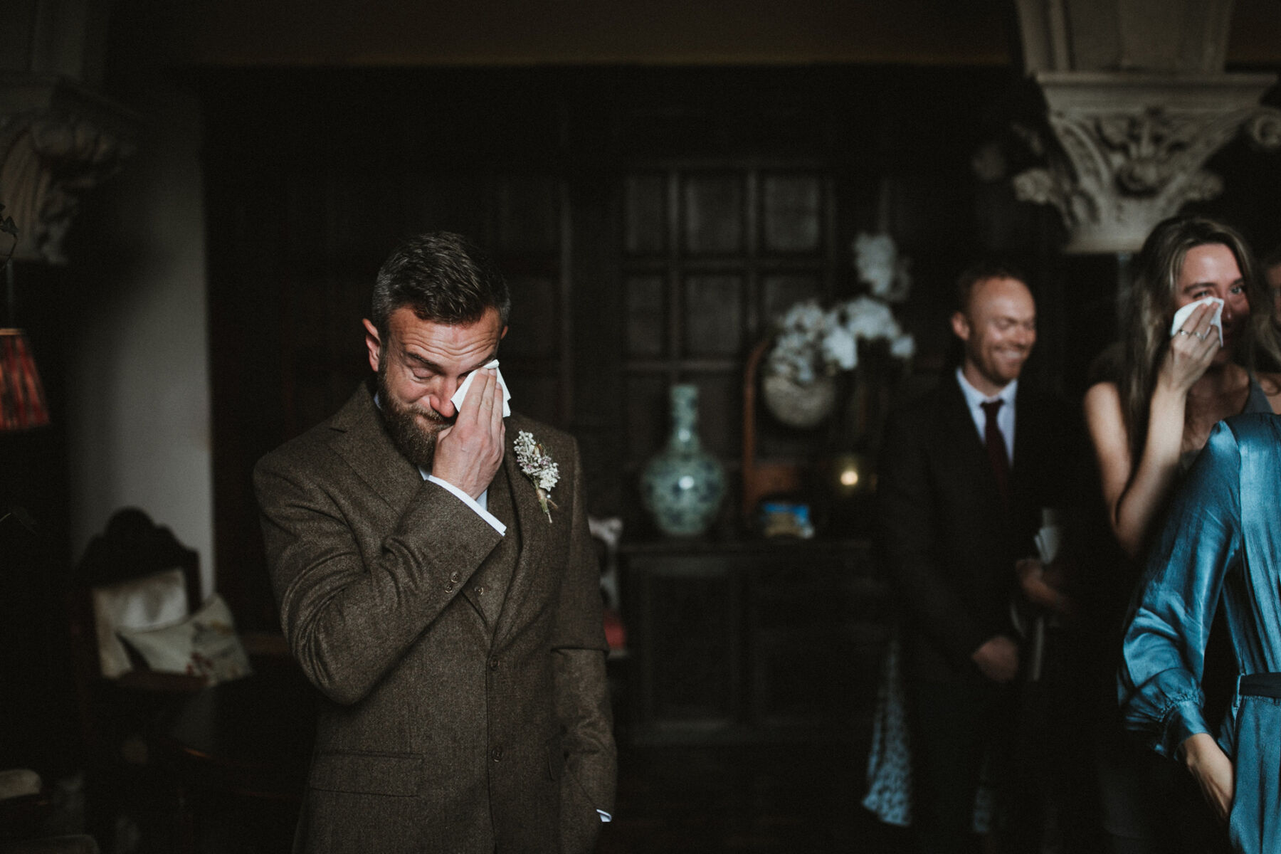 Groom wiping a tear from his eye as he waits for his bride.