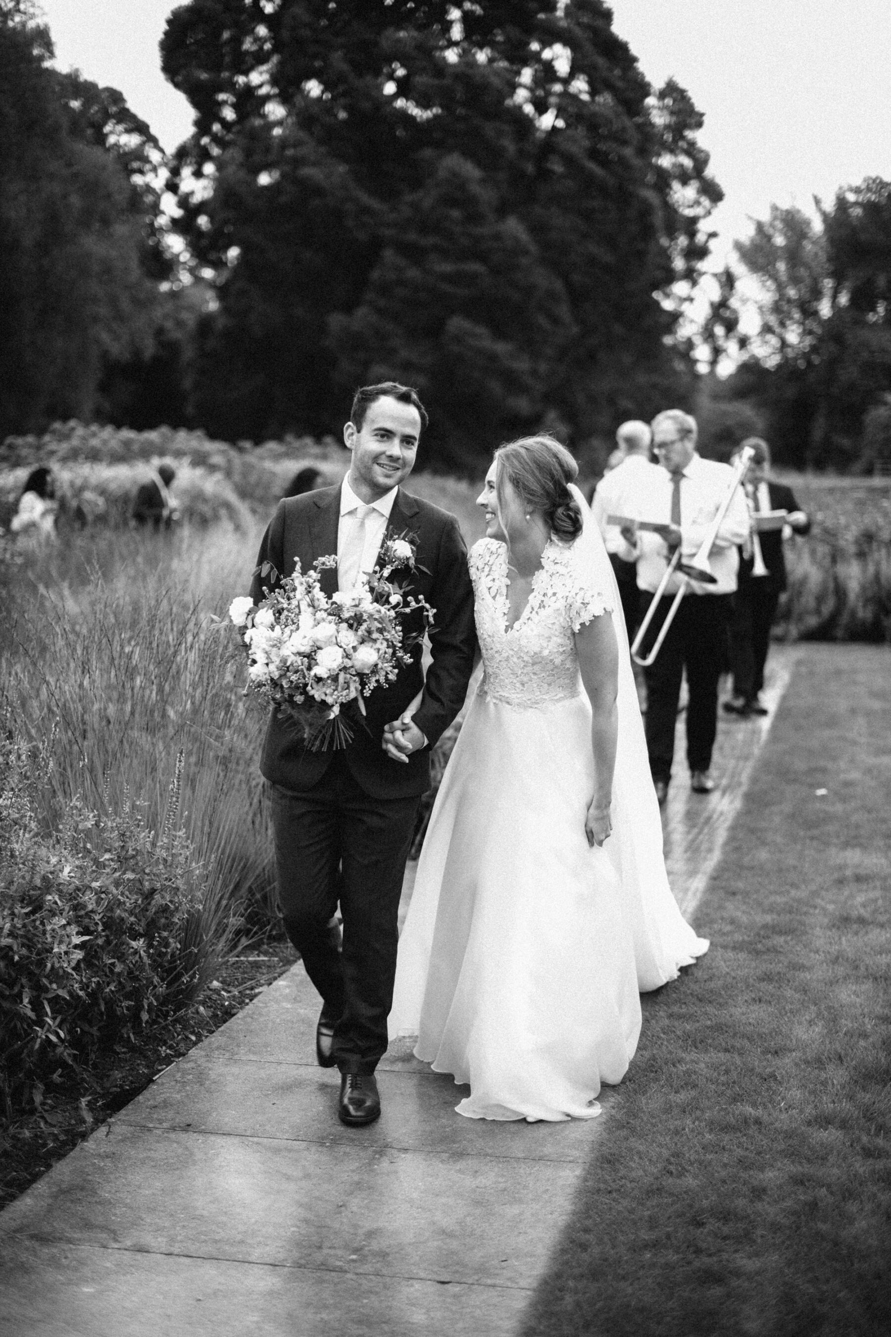 Black and white image of bride and groom walking outside at Middleton Lodge.