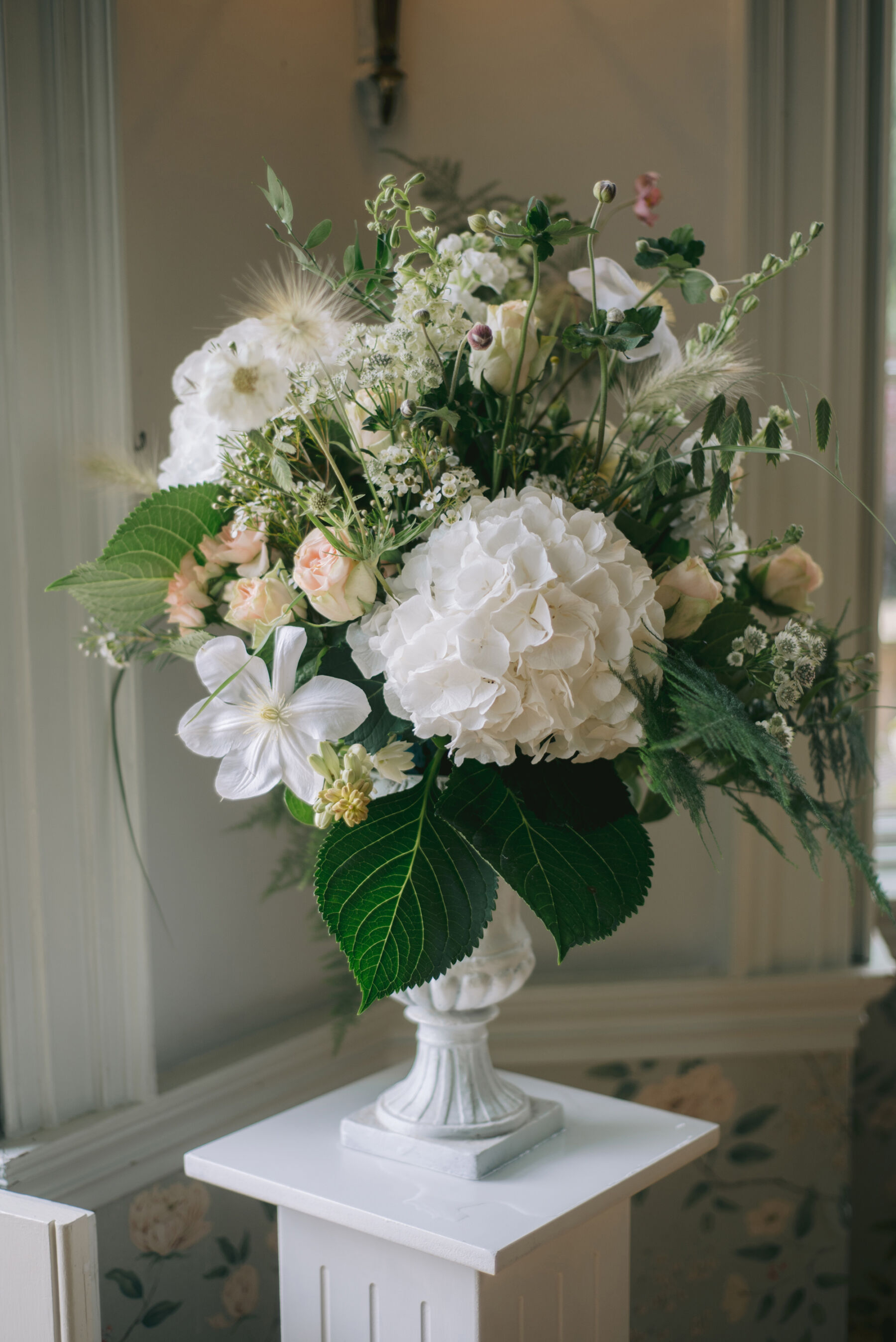 All green and white wedding flowers in a footed bowl vase.