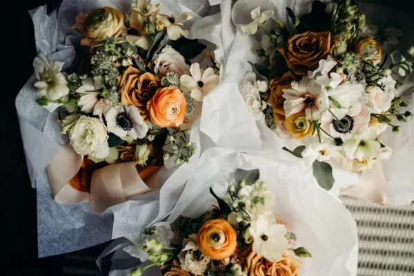 A close up shot of three bridal bouquets as they sit to be carried down the aisle. Delicately wrapped in tissue paper.