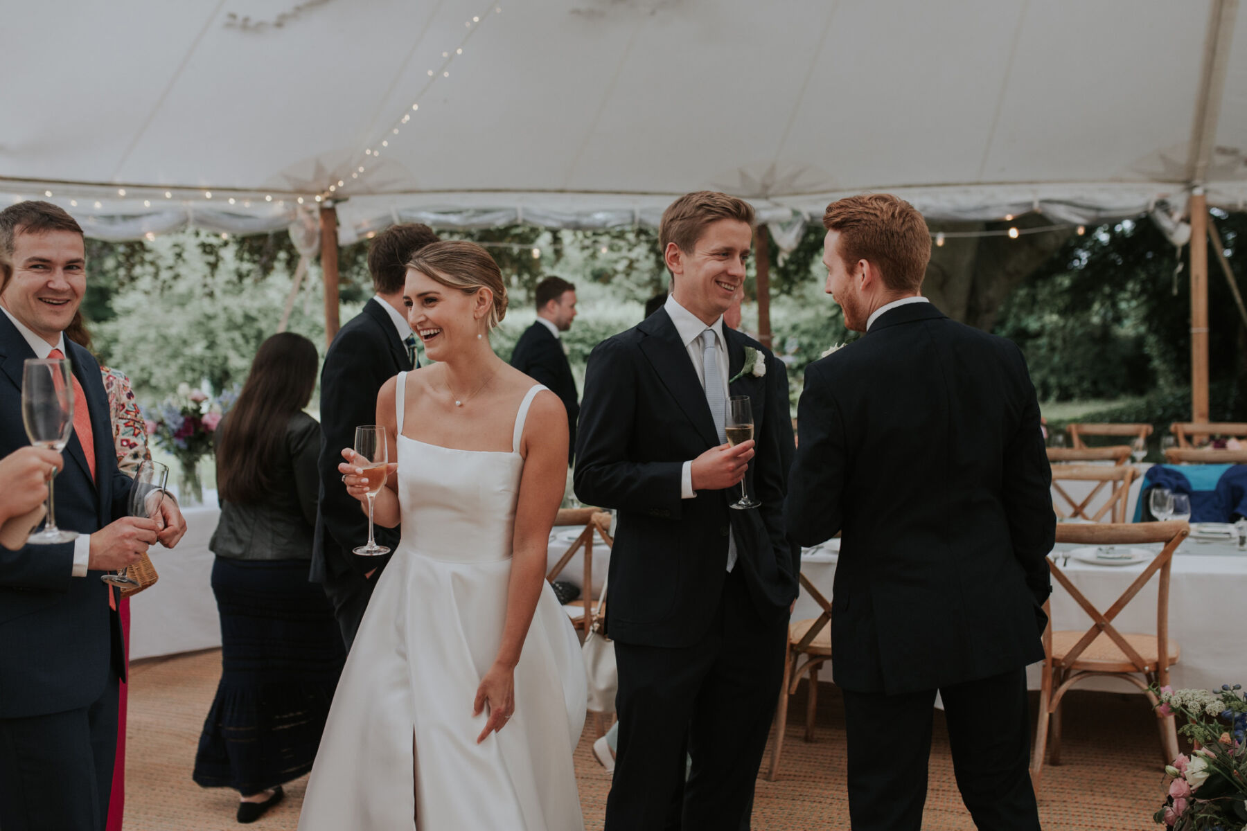 Bride inside a marquee holding a glass of champagne