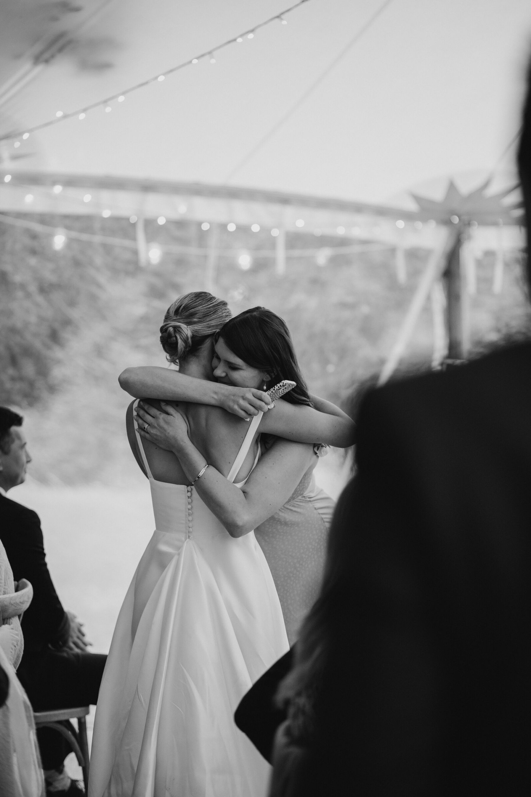 Bride hugging a guest inside a marquee at a wedding.