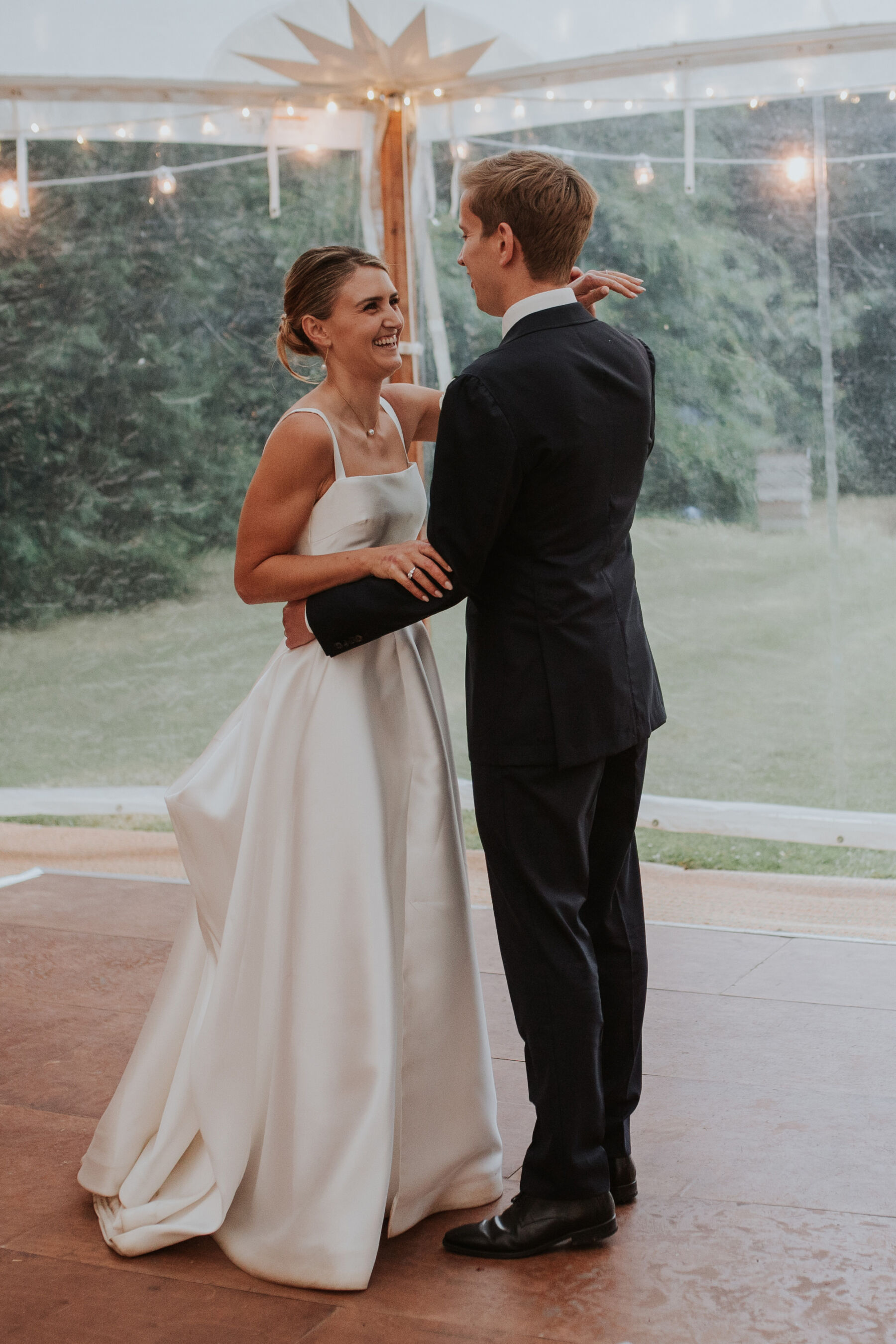 Bride wearing square neck Khya wedding dress on a dancefloor inside a marquee.