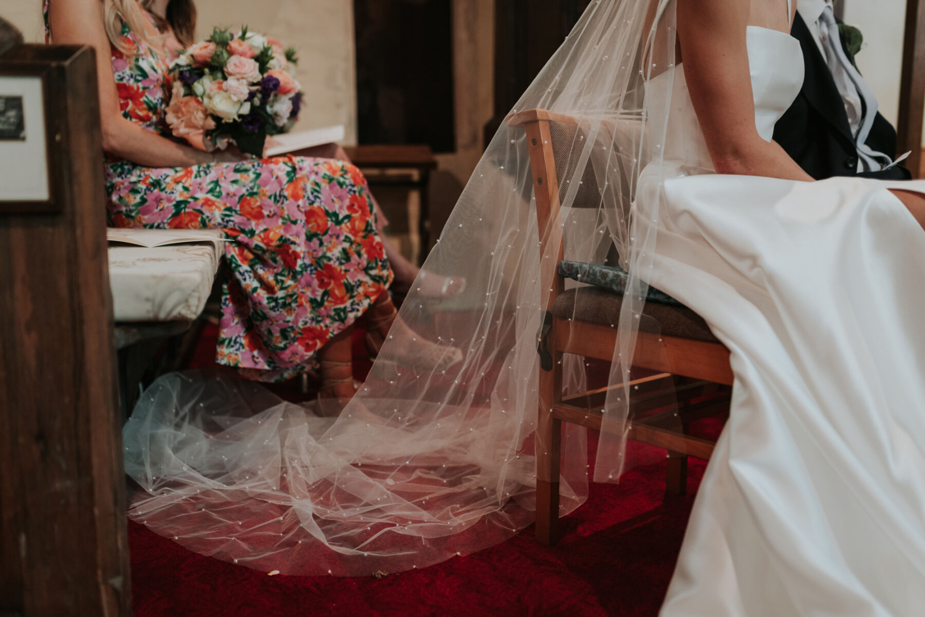 Bride sat in church wearing a long polka dot wedding veil