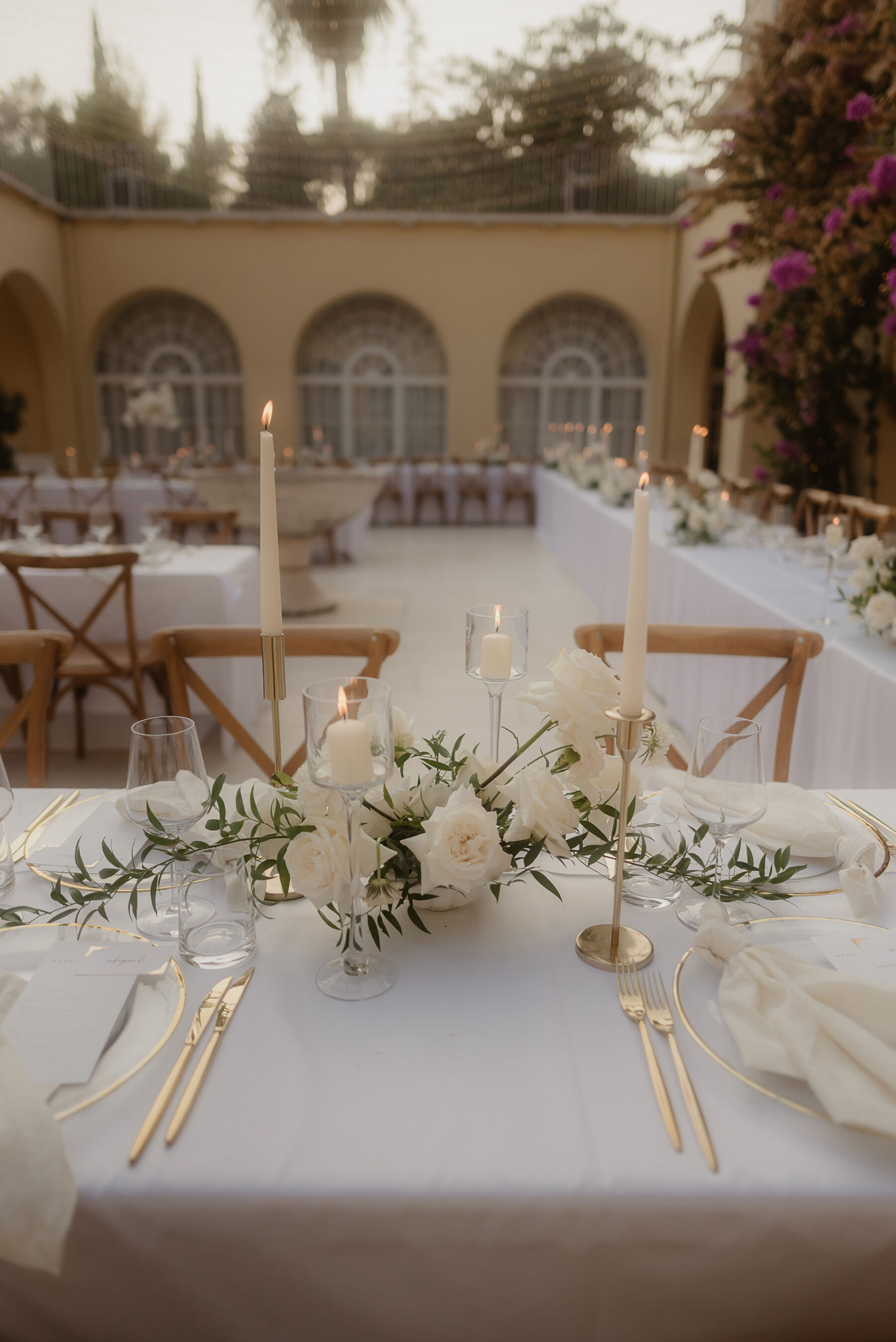 White taper candles and elegant white table flowers, white table linen and crossback chairs, wedding reception in Croatia