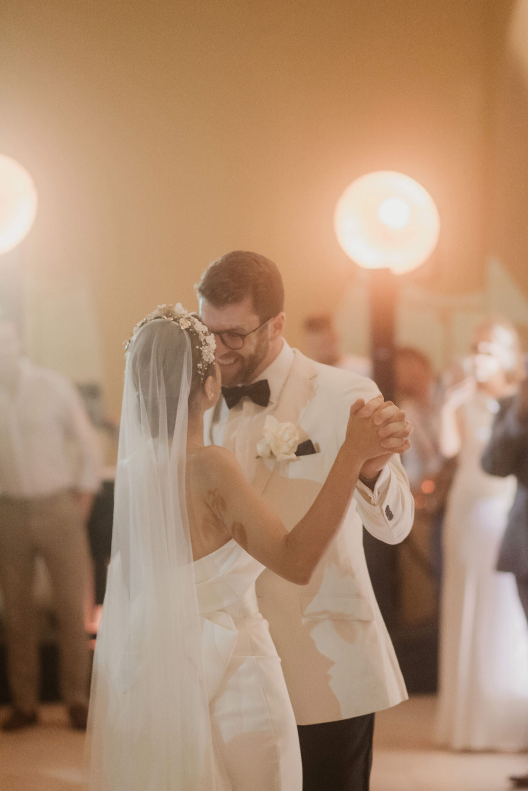 Groom in white tux taking the first dance with his bride.