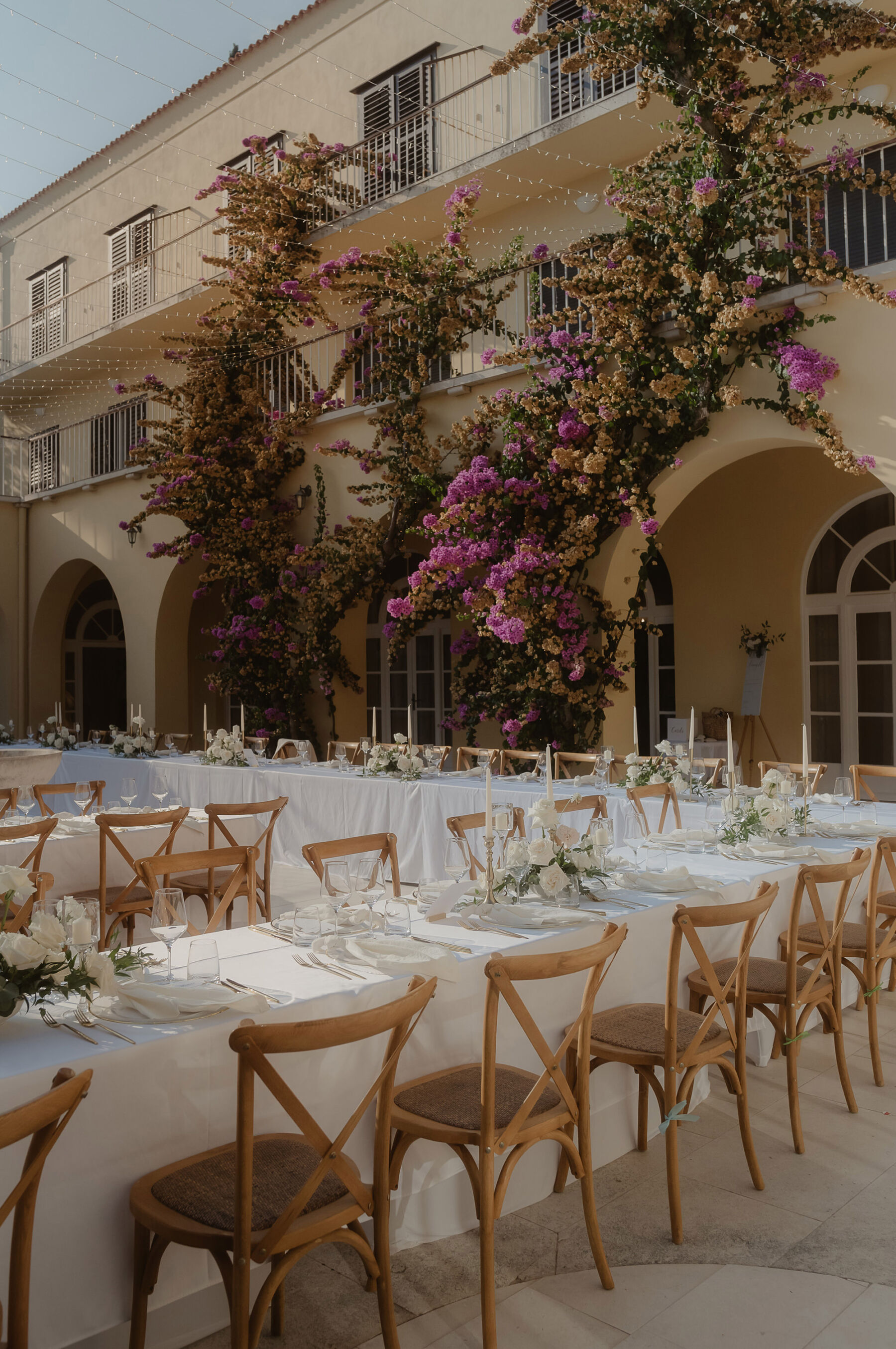 Wooden cross back chairs, white table linen & long tables, outdoor wedding reception, Croatia villa.